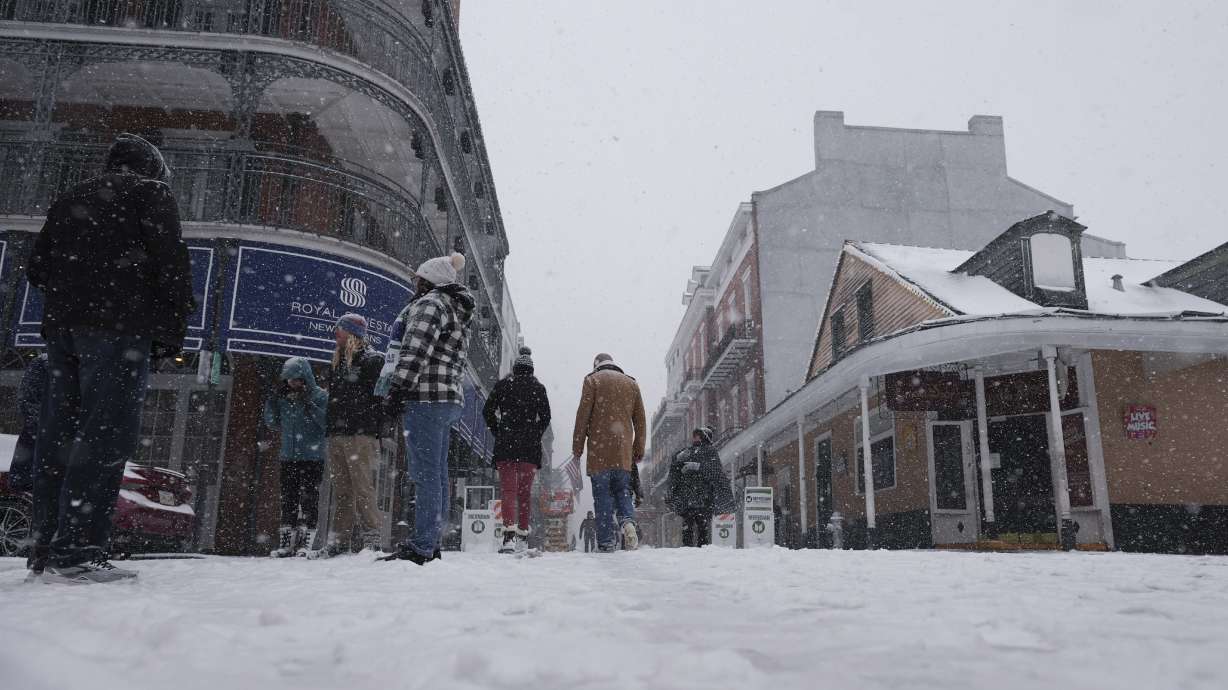 People walk in the French Quarter as snow falls in New Orleans, Tuesday.