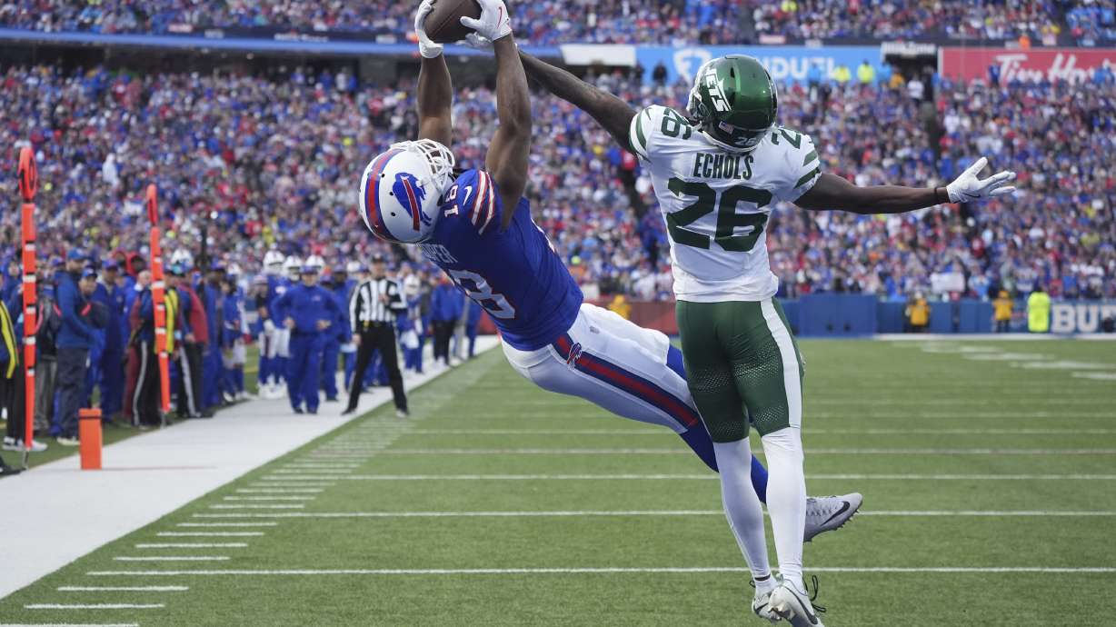 Buffalo Bills wide receiver Amari Cooper (18) catches a pass for a touchdown in front of New York Jets cornerback Brandin Echols (26) during the second half of an NFL football game, Sunday, Dec. 29, 2024, in Orchard Park, N.Y.