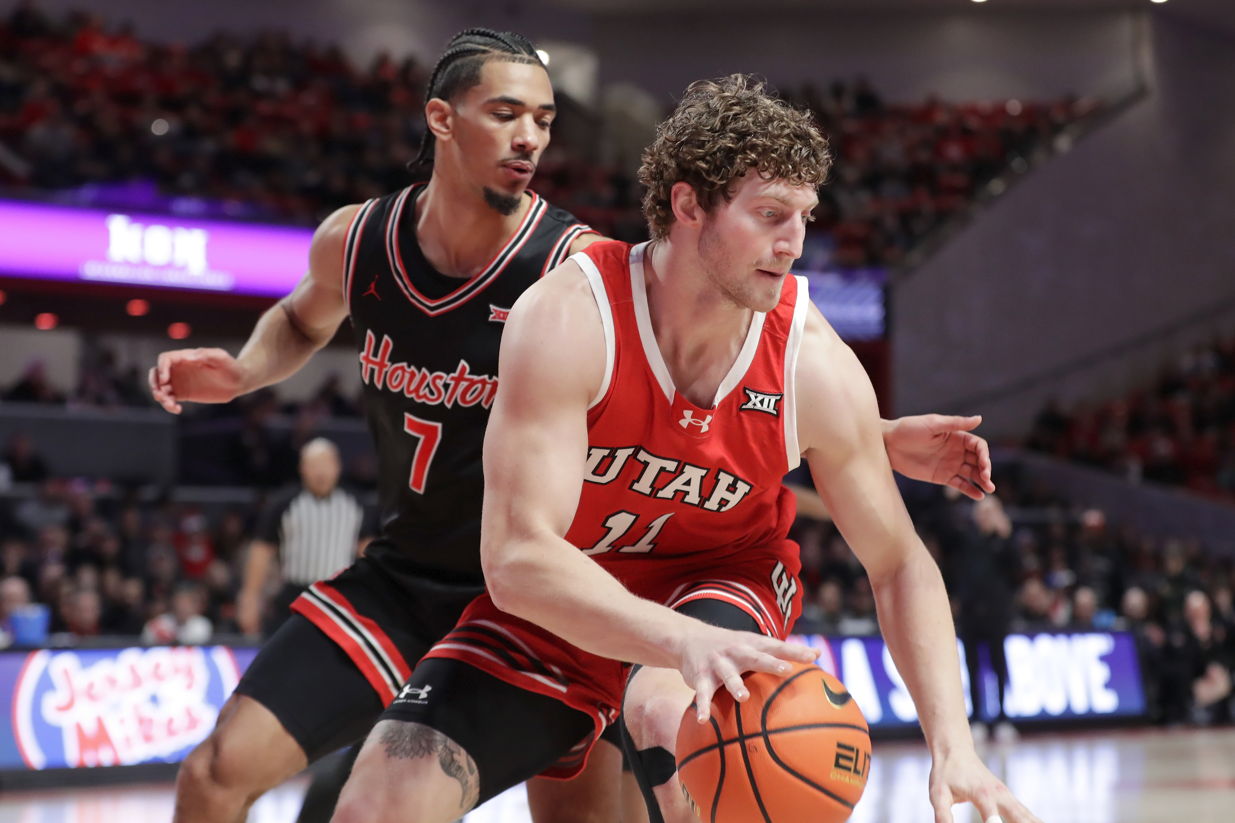Utah forward Caleb Lohner (11) attempts to drive around Houston guard Milos Uzan (7) during the first half of an NCAA college basketball game, Wednesday, Jan. 22, 2025, in Houston.