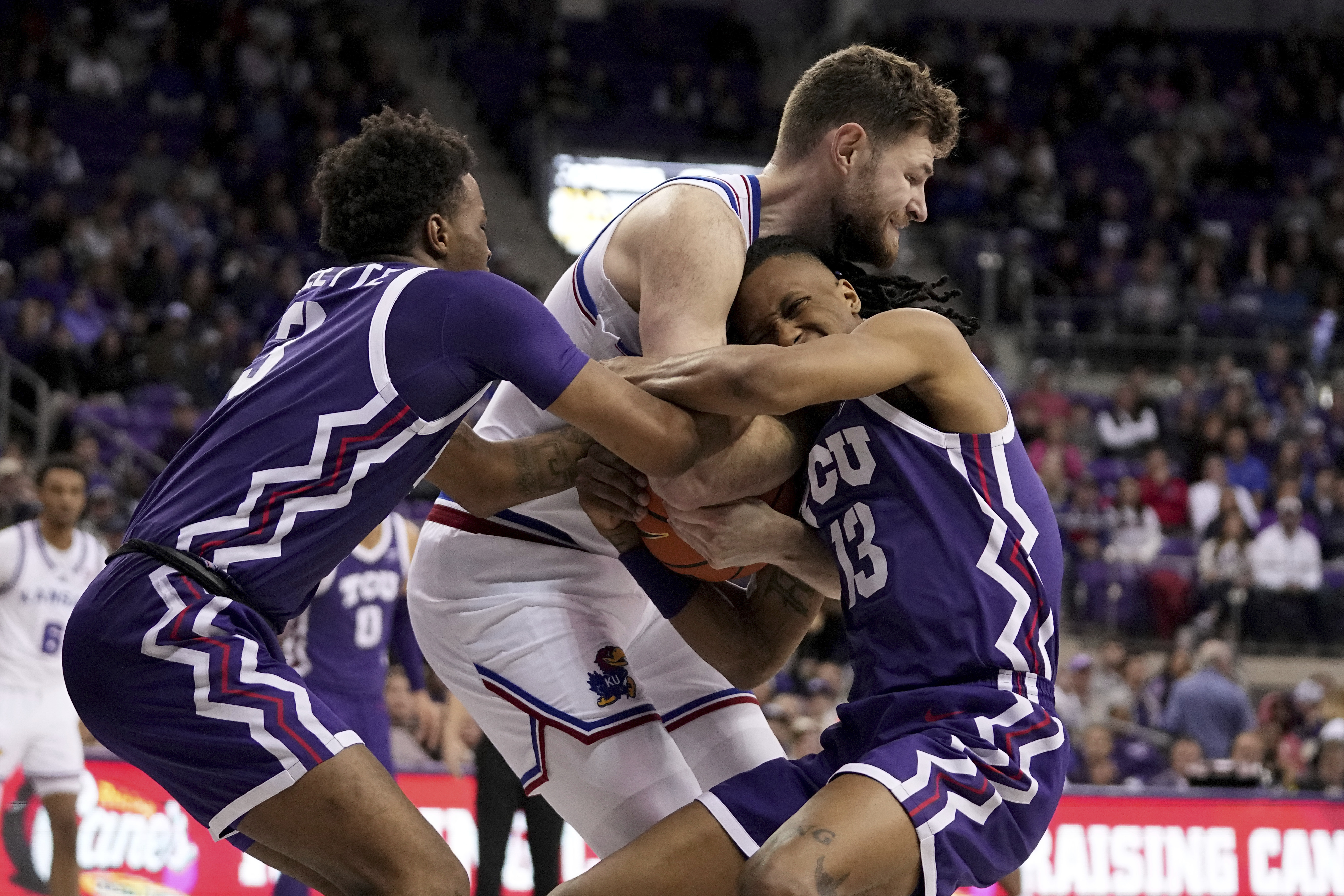 TCU's Vasean Allette, left, and Trazarien White (13) wrestle for control of the ball against Kansas center Hunter Dickinson, center, in the second half of an NCAA college basketball game in Fort Worth, Texas, Wednesday, Jan. 22, 2025.