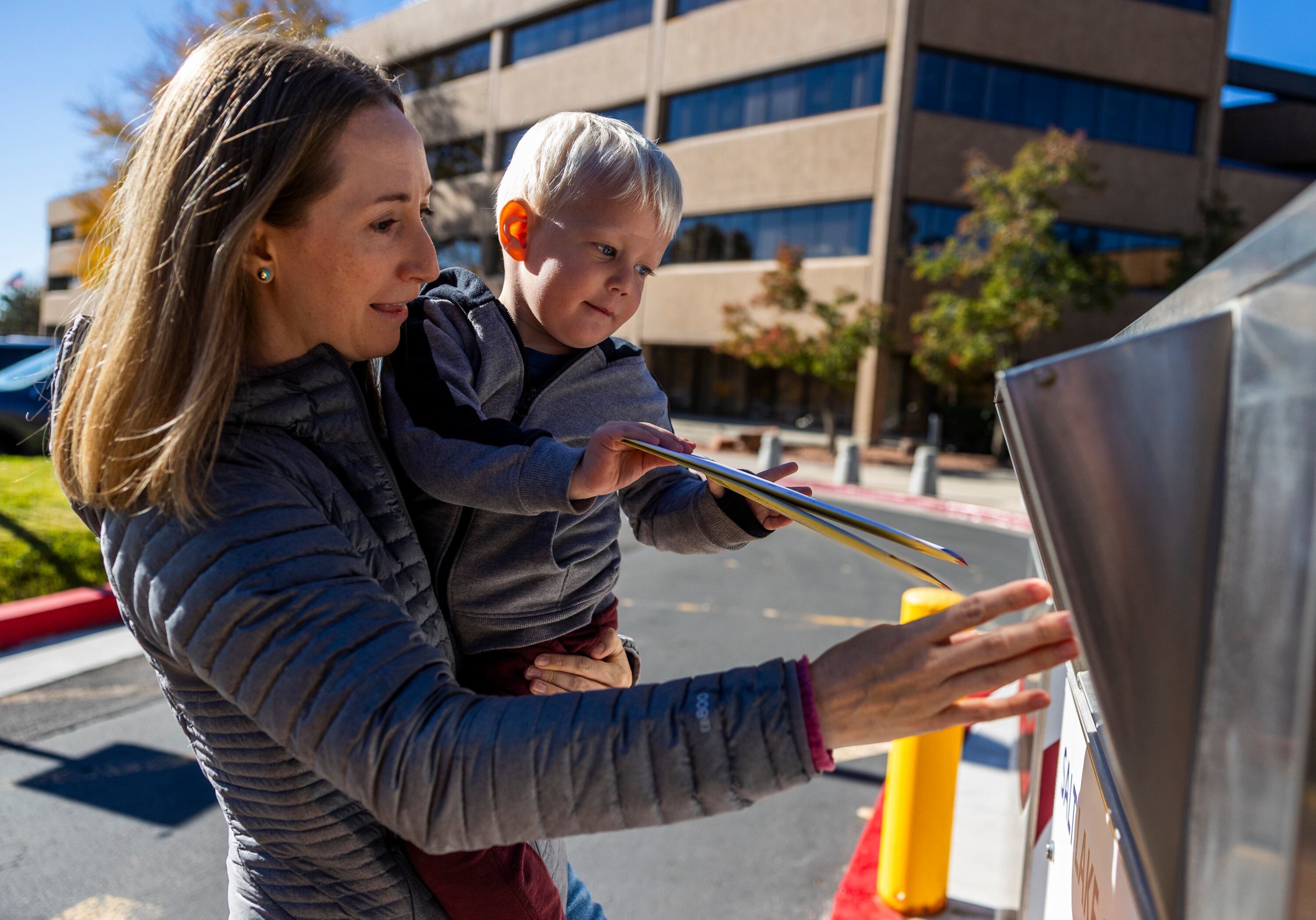 Katherine Kitterman holds her 2-year-old son, Ethan Roberts, as he places her ballot in a drop box outside of the Salt Lake County Government Center in Salt Lake City on Nov. 4, 2024. Kitterman said that she brought her son with her so that he can see her voting and follow her example as an adult.