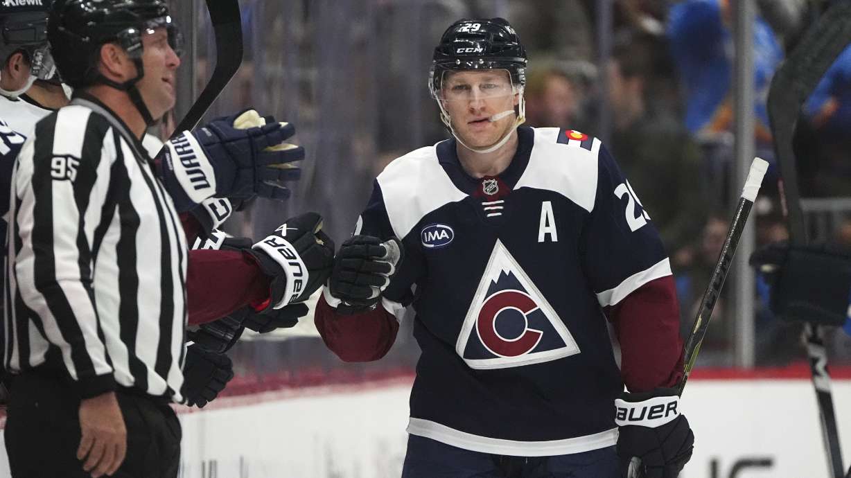 Colorado Avalanche center Nathan MacKinnon, right, is congratulated as he passes the team box after scoring a goal against the Winnipeg Jets in the second period of an NHL hockey game, Wednesday, Jan. 22, 2025, in Denver.