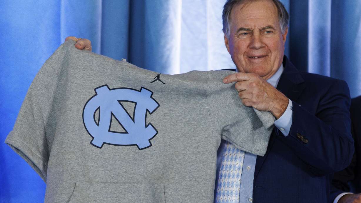 FILE - New North Carolina football coach Bill Belichick holds up a UNC branded sleeveless hoodie presented to him during an NCAA college football news conference announcing his hiring, Dec. 12, 2024, in Chapel Hill, N.C.