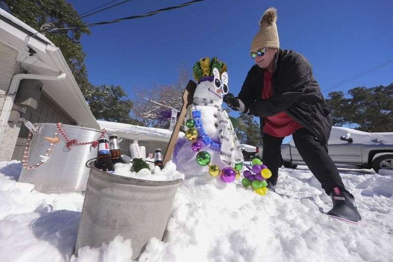 Stacy Centanni refreshes her Mardi Gras festooned snowman as it melts, the day after a record-setting snowstorm in River Ridge, La., a suburb of New Orleans, Wednesday.