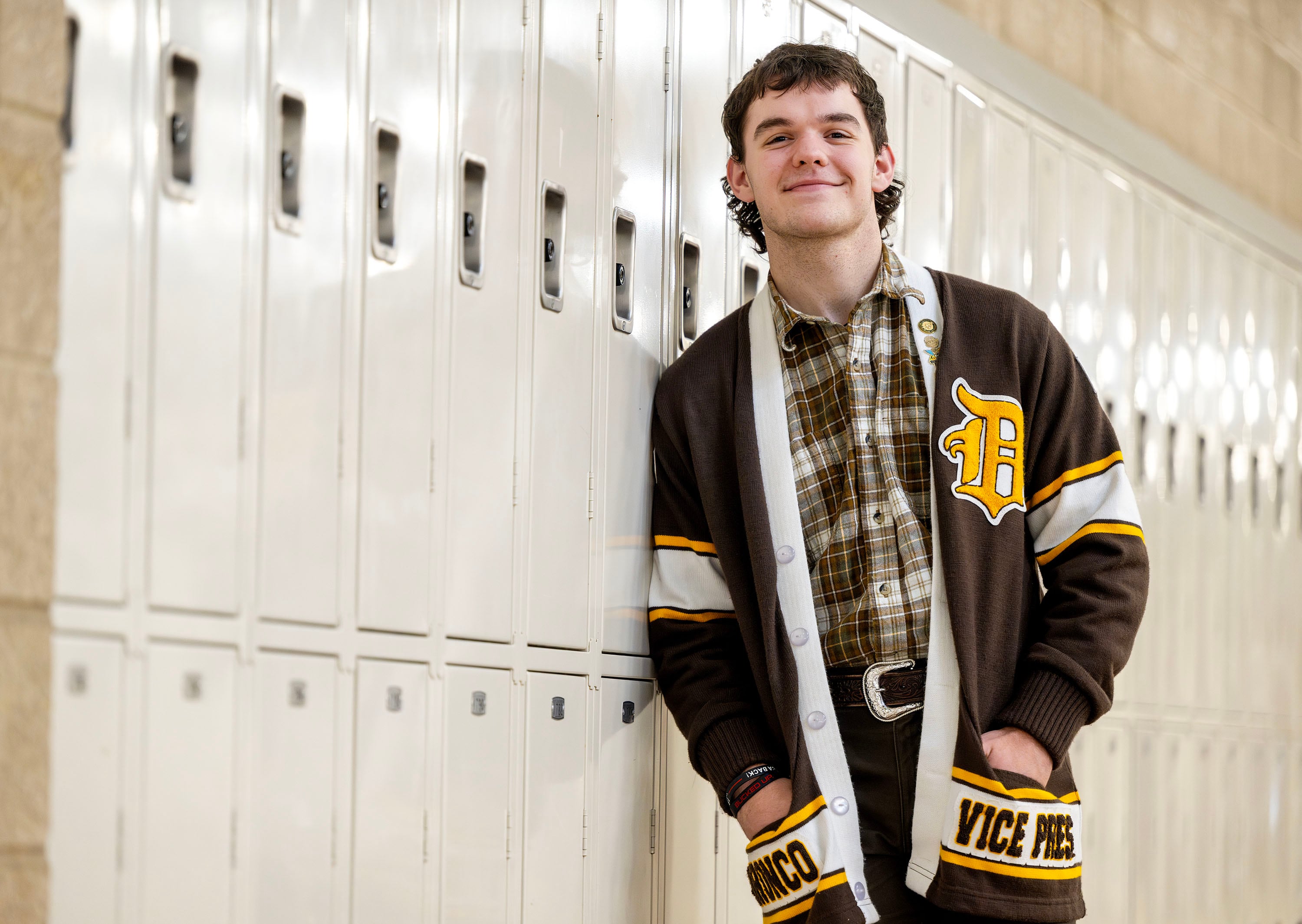 Bronco Maxfield poses for a photo at a wall of lockers that he and other Davis High School student leaders hope to transform into a remembrance and honor wall of former Darts who served in the armed forces. The students were working to verify names on Jan. 17.  Maxfield is the student who came up with the idea of the wall.