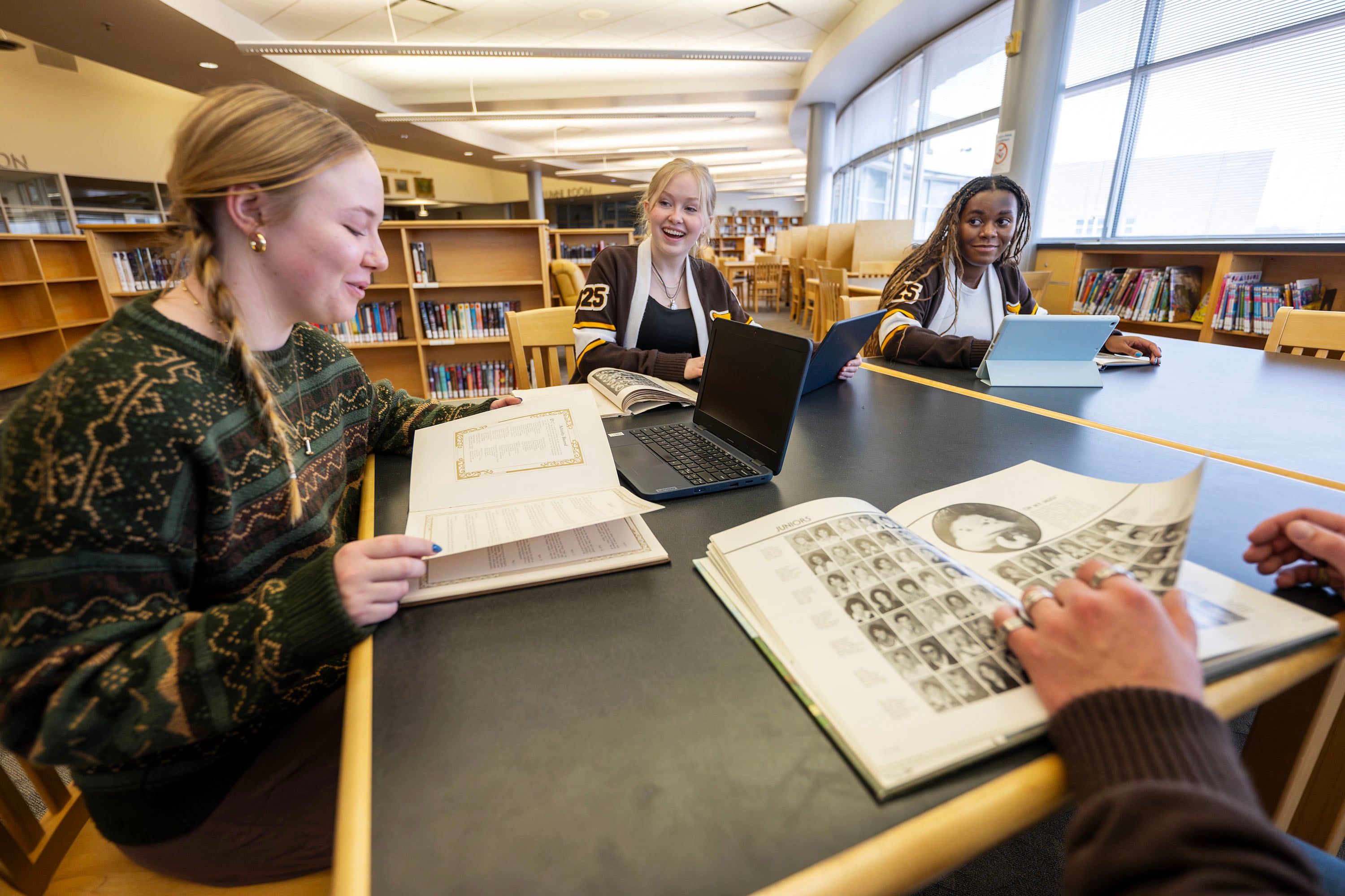 Davis High School student leaders Isabelle Koenig, Coroline Taylor, Makenna Pearce and Konner Gallup talk as they look through old yearbooks, trying to find any info of former students who might have served in the armed forces, on Jan. 17.