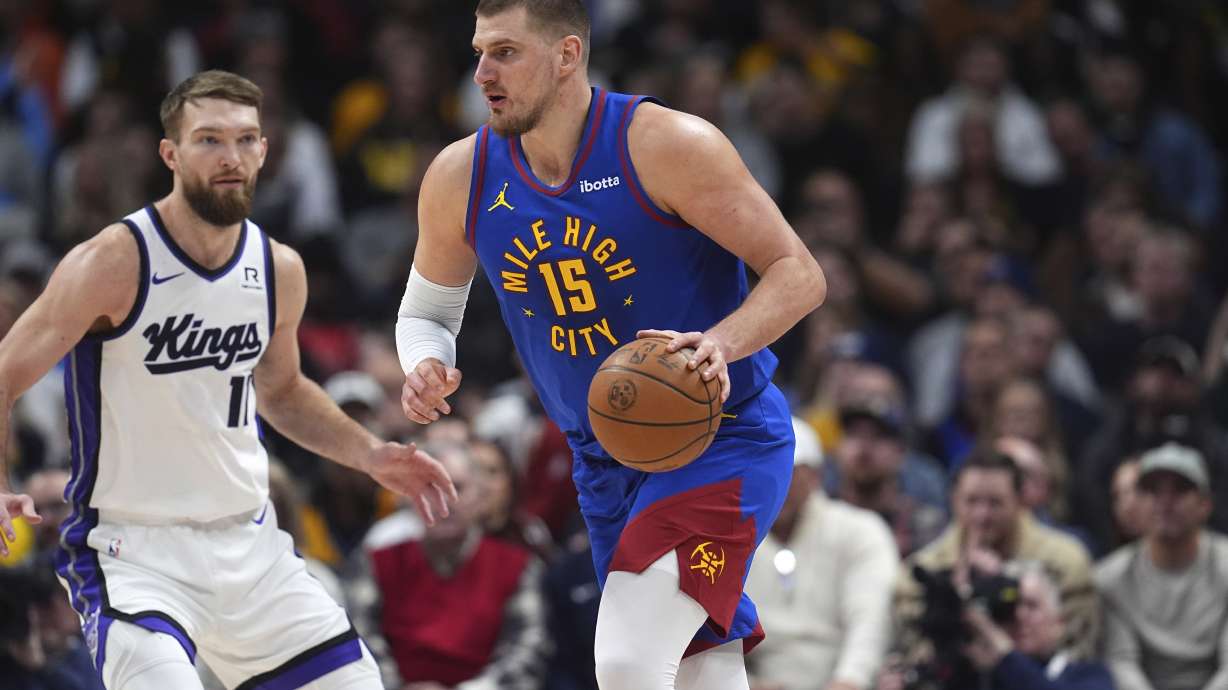 Denver Nuggets center Nikola Jokic, right, looks to pass the ball as Sacramento Kings forward Domantas Sabonis defends in the first half of an NBA basketball game Thursday, Jan. 23, 2025, in Denver.