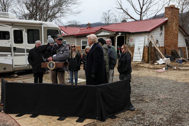 President Donald Trump and first lady Melania Trump listen to a man, carrying a child, affected by Hurricane Helene, as they tour areas devastated by the hurricane to assess recovery efforts in Swannanoa, North Carolina, Friday.