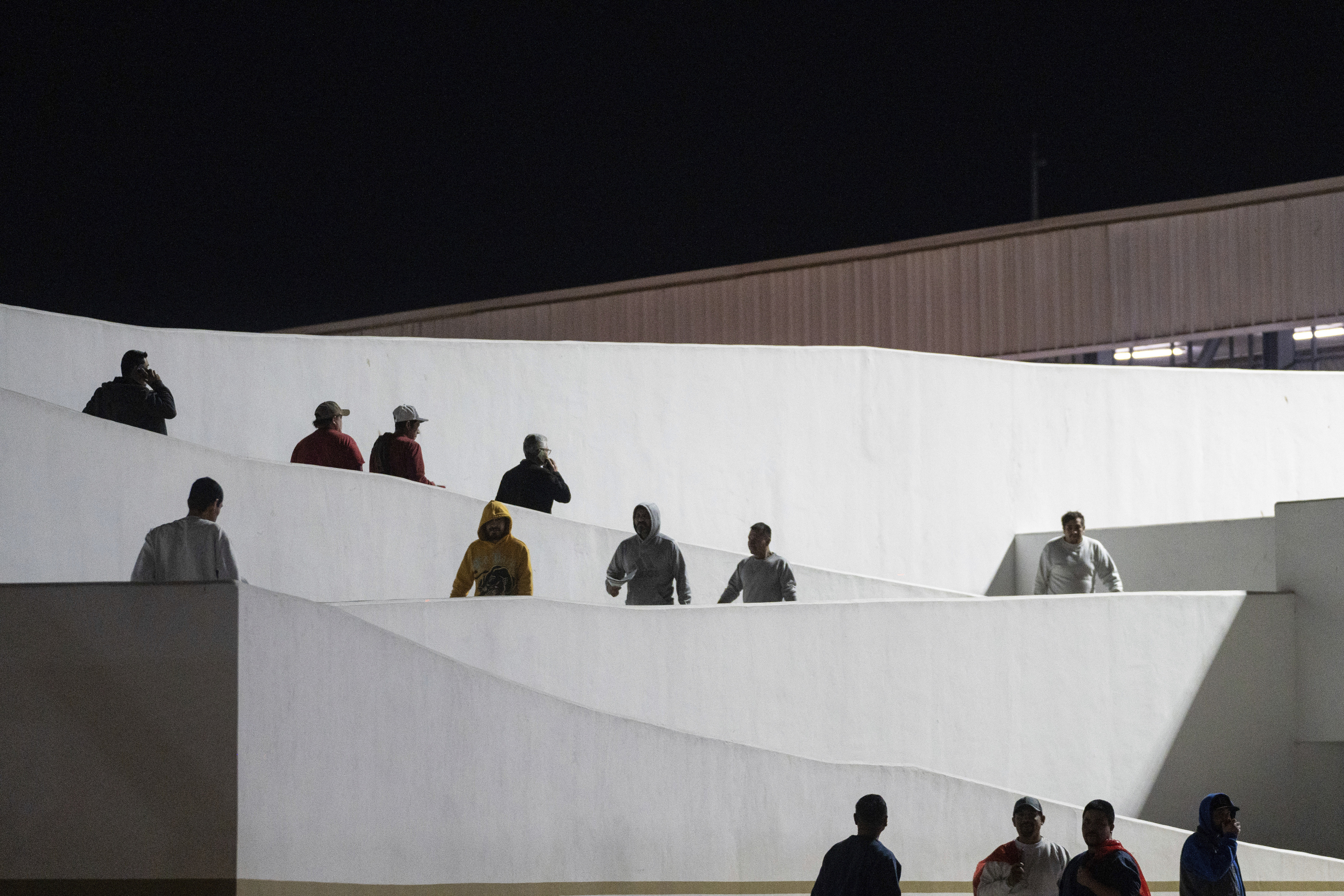Migrants walk into Mexico after being deported from the U.S. at El Chaparral pedestrian border bridge in Tijuana, Mexico, on Tuesday.