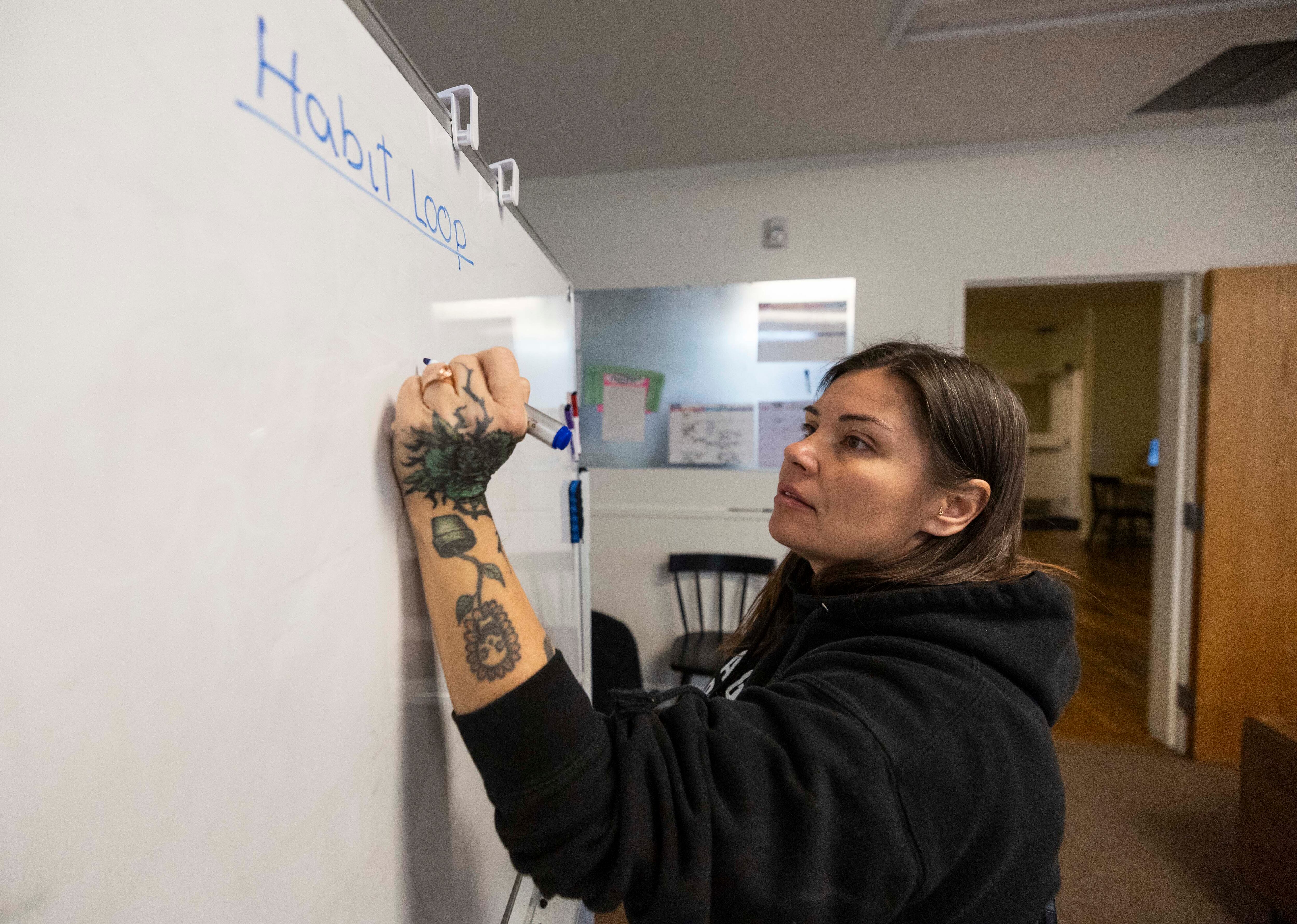 Other Side Village coach Tiffany Holdaway writes on a white board during a skills lesson about habits at the Other Side Village campus in Murray on Friday.