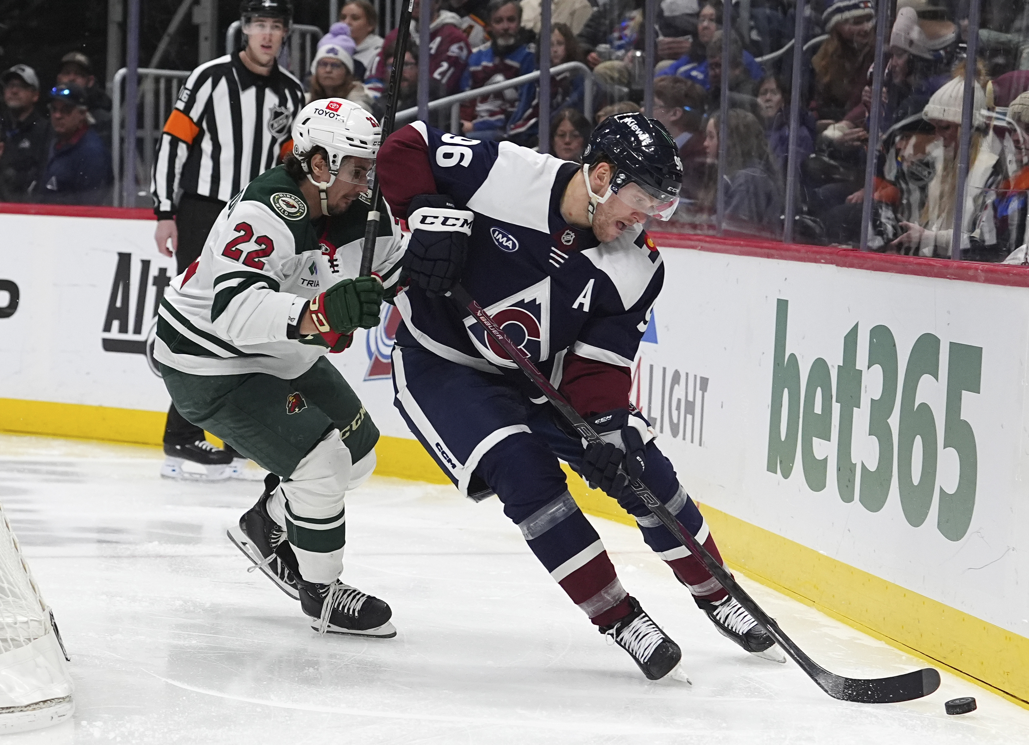 Colorado Avalanche right wing Mikko Rantanen, right, collects the puck as Minnesota Wild center Marat Khusnutdinov defends in the third period of an NHL hockey game Monday, Jan. 20, 2025, in Denver.