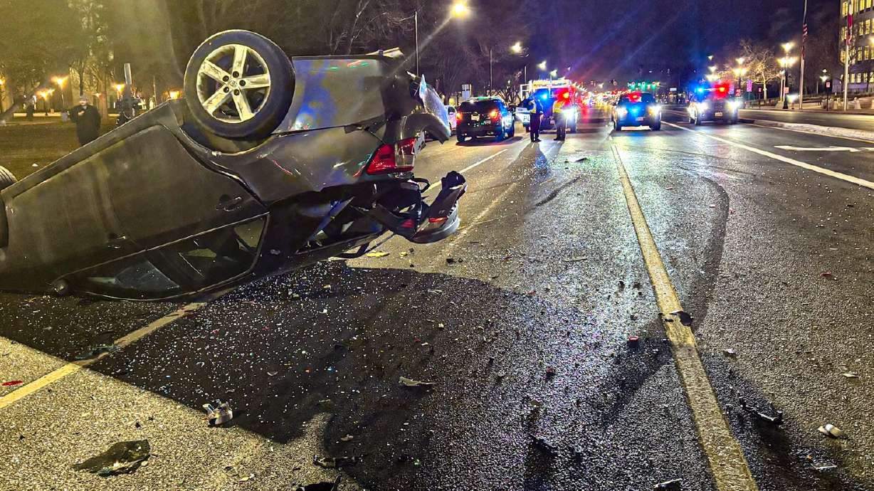 An overturned car rests on its roof Friday night while multiple police cars secure the scene at 400 S. State Street following a suspected impaired driving crash.