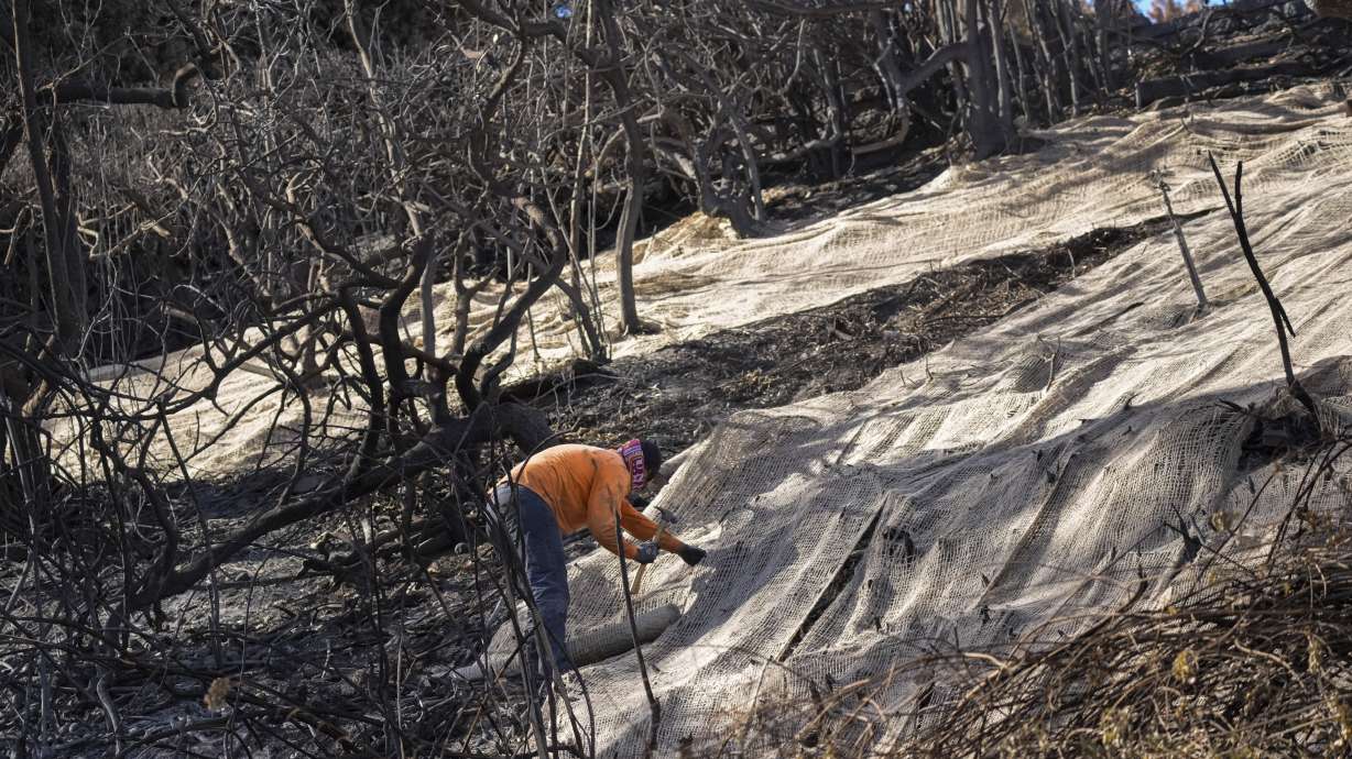 Workers secure a net to prevent mudslides over the burned side of a mansion in the Pacific Palisades neighborhood of Los Angeles, Friday.