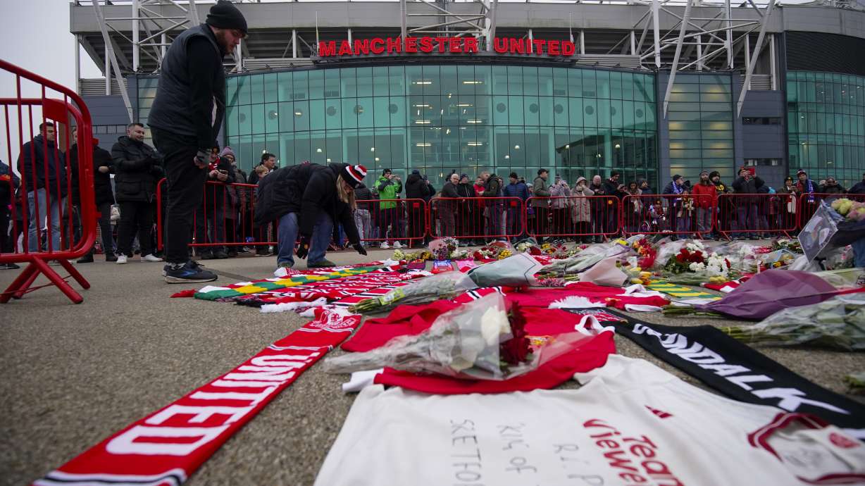 People lay flowers in memory of Denis Law prior the English Premier League soccer match between Manchester United and Brighton and Hove Albion, at the Old Trafford stadium in Manchester, England, Sunday, Jan. 19, 2025.