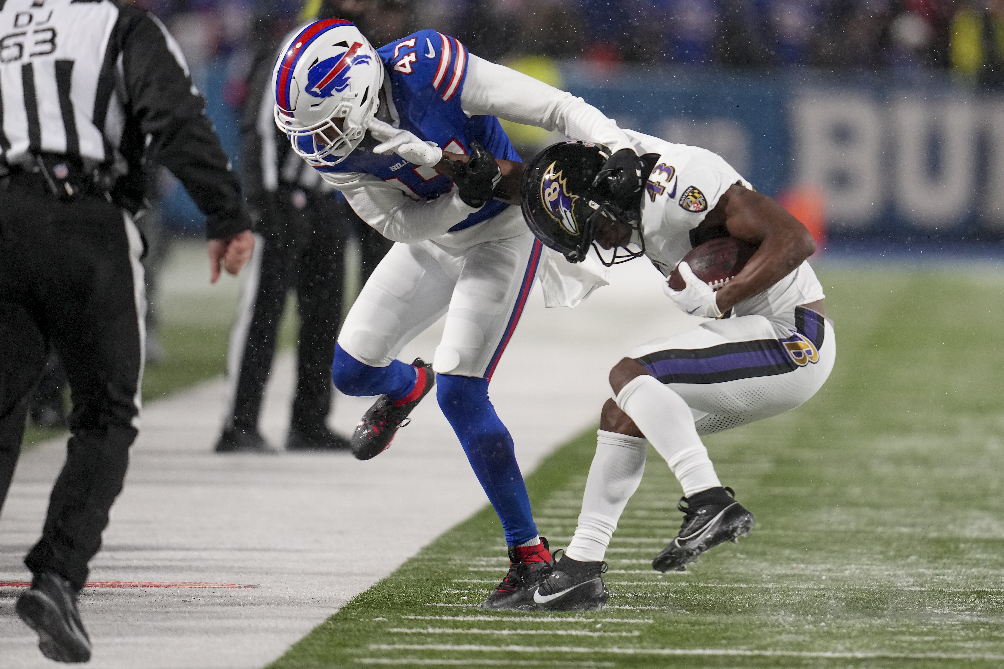 Baltimore Ravens running back Justice Hill (43) tries to avoid a tackle by Buffalo Bills cornerback Christian Benford (47) during the second quarter of an NFL divisional playoff football game, Sunday, Jan. 19, 2025, in Orchard Park, N.Y. 