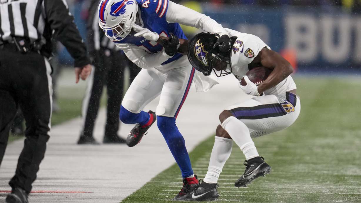 Baltimore Ravens running back Justice Hill (43) tries to avoid a tackle by Buffalo Bills cornerback Christian Benford (47) during the second quarter of an NFL divisional playoff football game, Sunday, Jan. 19, 2025, in Orchard Park, N.Y.
