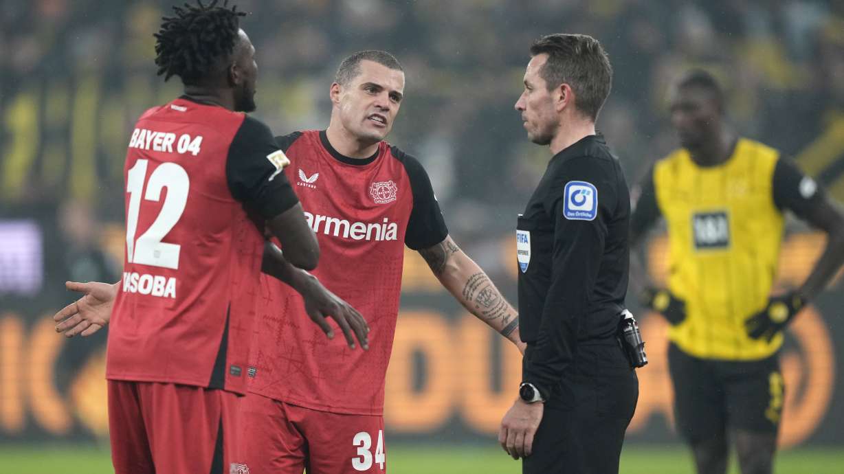 Leverkusen's Granit Xhaka, centre, argues with referee Tobias Stieler during the German Bundesliga soccer match between Borussia Dortmund and Bayer Leverkusen at the Signal-Iduna Park in Dortmund, Germany, Friday, Jan. 10, 2025.