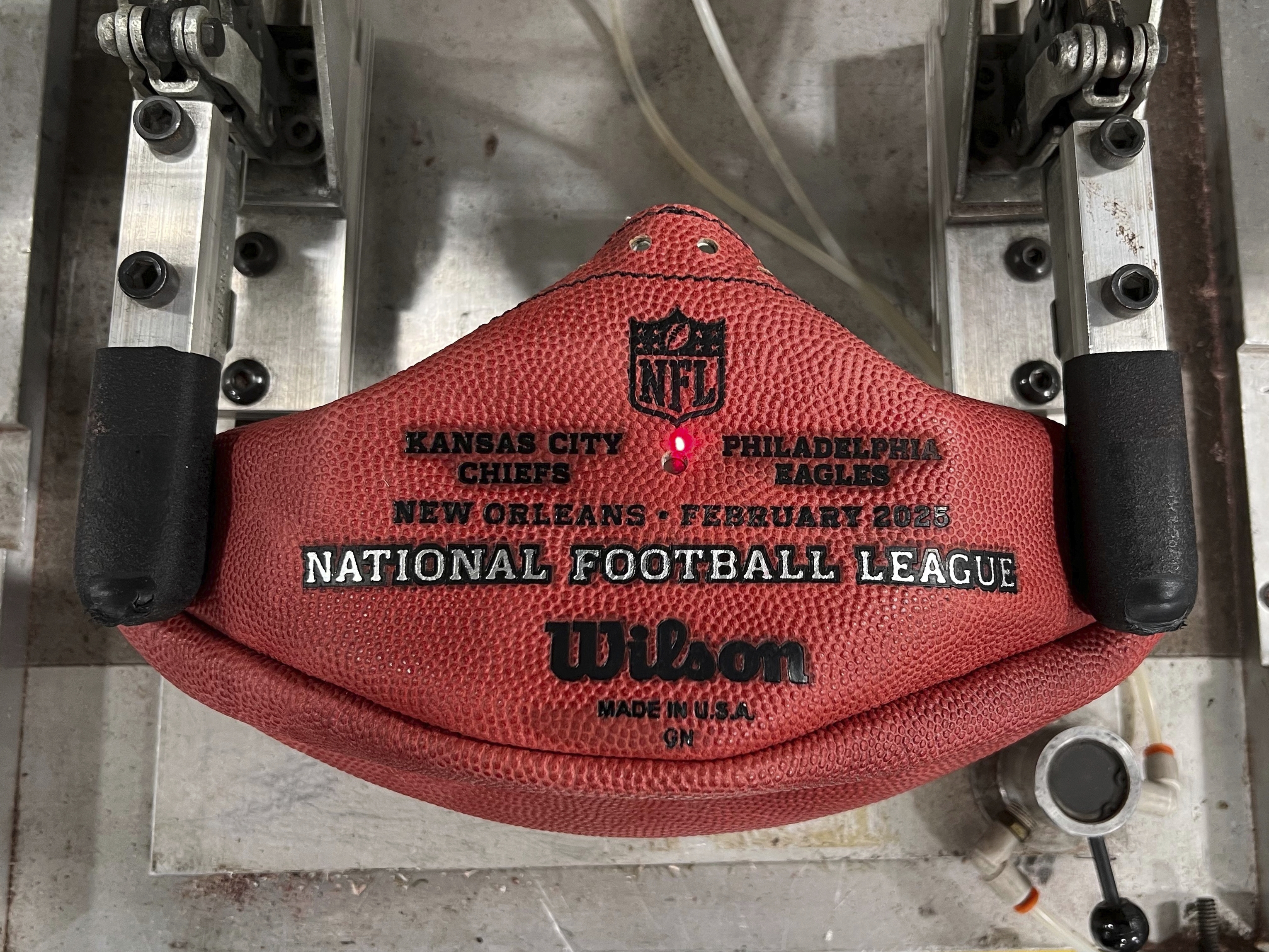 A machine imprints the names of the Philadelphia Eagles and the Kansas City Chiefs onto a football for the upcoming Super Bowl matchup at the Wilson Sporting Goods football factory, Monday, January 27, 2025, in Ada, Ohio. 