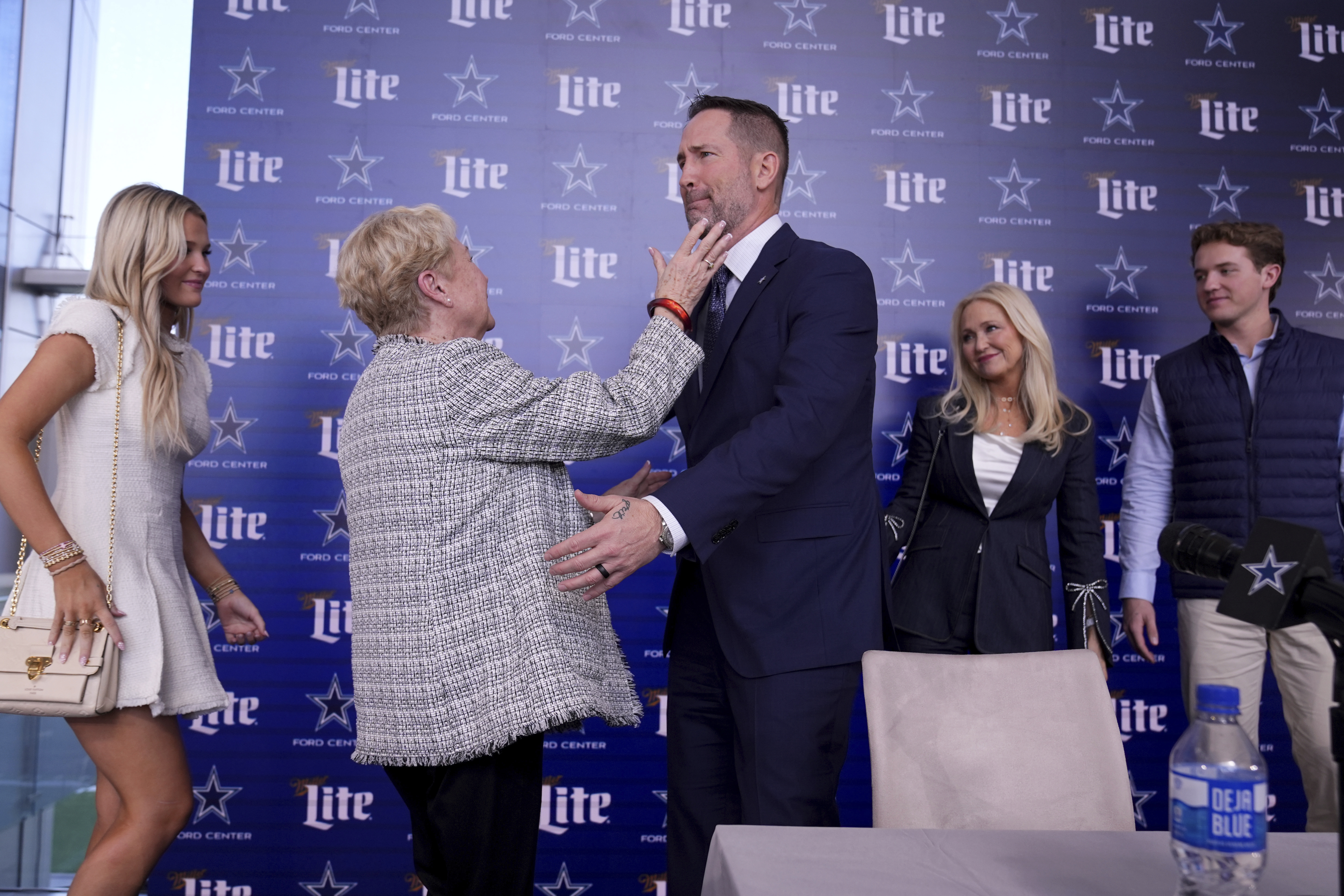 Dallas Cowboys new head coach Brian Schottenheimer, center right, becomes emotional as he reaches to hug his mother, Pat Schottenheimer, center left as his daughter, Savannah, from left rear, wife Gemmi and son Sutton, right rear, look on after a news conference where at the team's headquarters in Frisco, Texas, Monday, Jan. 27, 2025. 