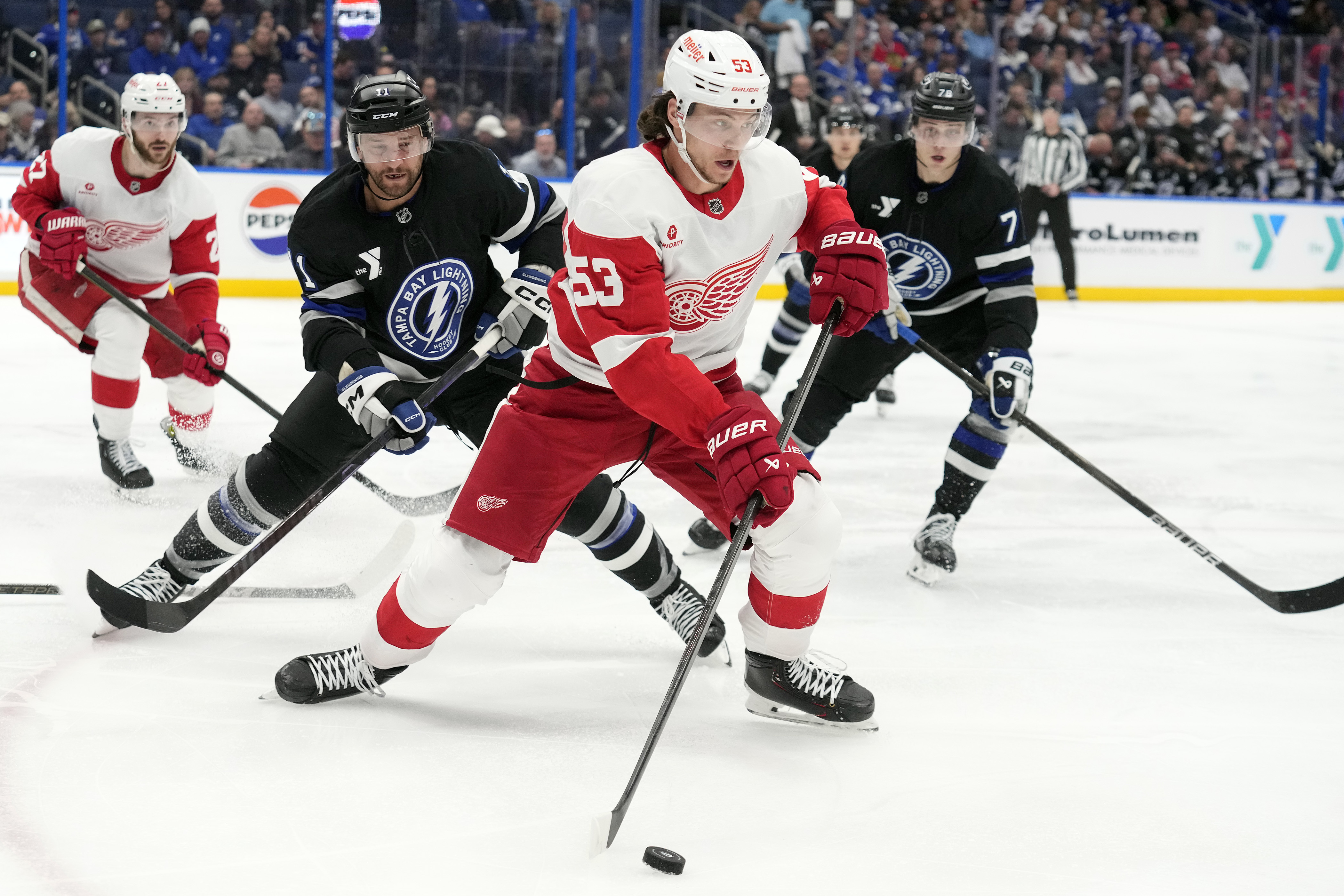 Detroit Red Wings defenseman Moritz Seider (53) carries the puck between Tampa Bay Lightning center Luke Glendening (11) and defenseman Emil Lilleberg (78) during the third period of an NHL hockey game Saturday, Jan. 18, 2025, in Tampa, Fla.