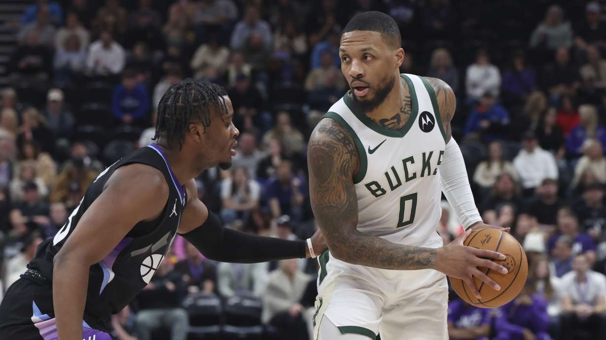 Milwaukee Bucks guard Damian Lillard (0) looks to pass the ball against Utah Jazz guard Isaiah Collier, left, during the first quarter of an NBA basketball game, Monday, Jan. 27, 2025, in Salt Lake City.