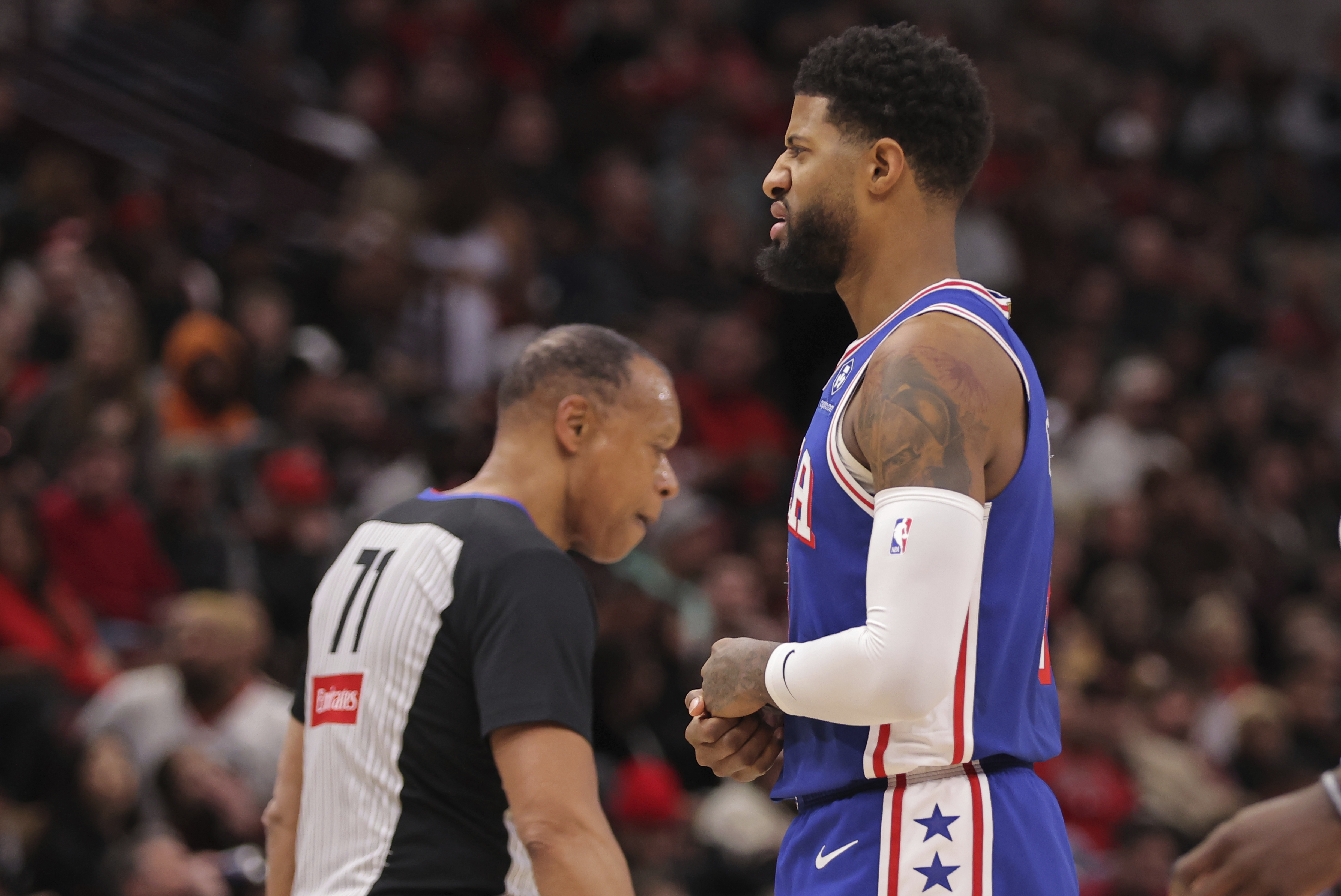 Philadelphia 76ers forward Paul George grabs his hand as he walks back to the bench during the first half of an NBA basketball game against the Chicago Bulls, Saturday, Jan. 25, 2025, in Chicago. 
