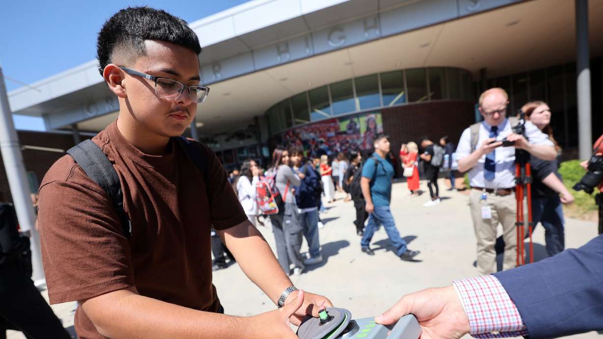 A student unlocks a Yondr pouch that has his cellphone inside on a magnetic unlocking base as he leaves Granger High School in West Valley City on Aug. 26, 2024. If an education bill passes, Utah will prohibit the use of cellphones during school.