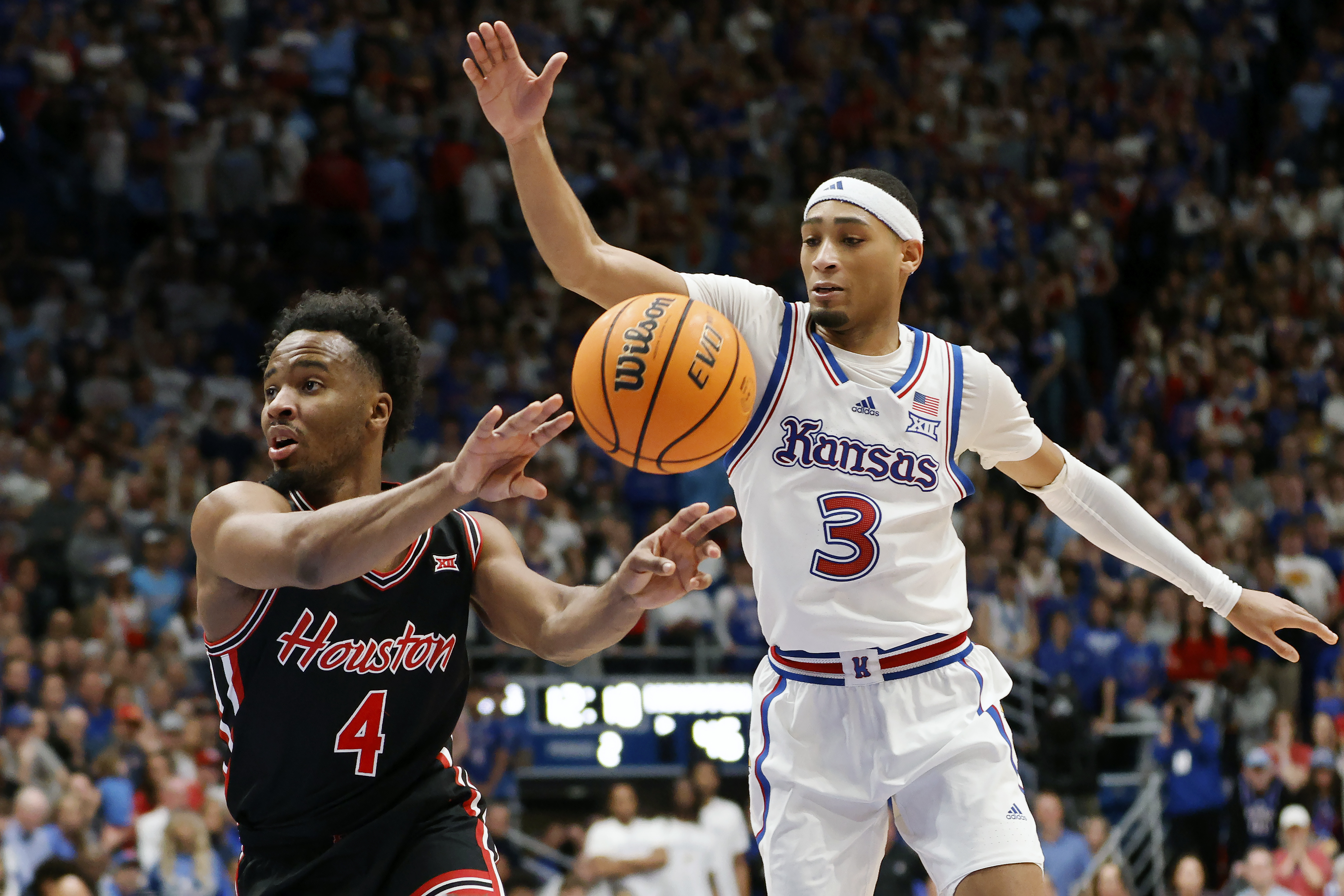 Houston guard L.J. Cryer (4) passes the ball as Kansas guard Dajuan Harris Jr. (3) defends during the second half of an NCAA college basketball game, Saturday, Jan. 25, 2025, in Lawrence, Kan.