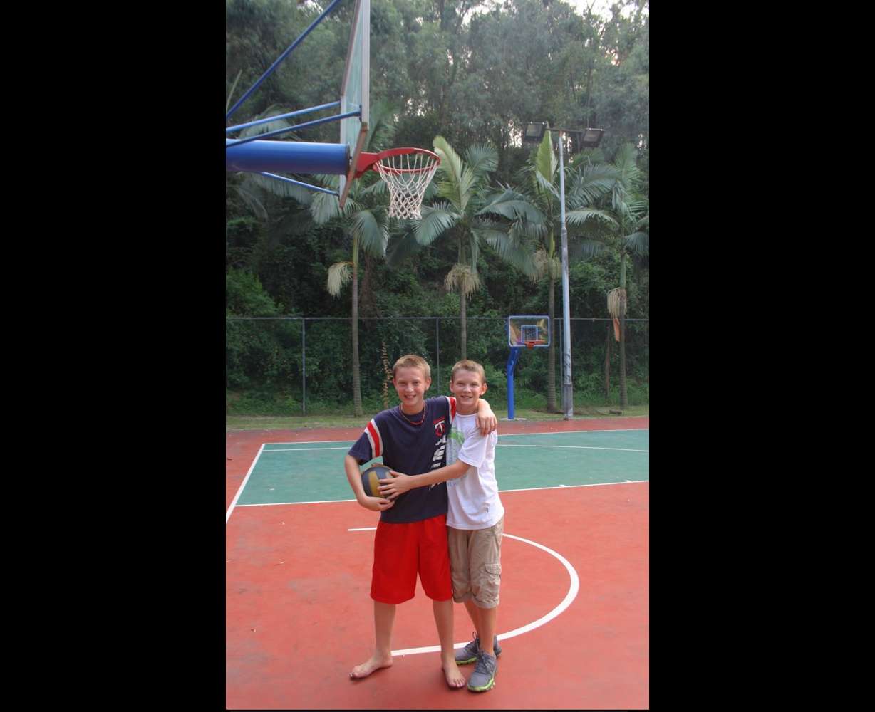 Mason and Gabe Madsen hug while on a basketball court in China.