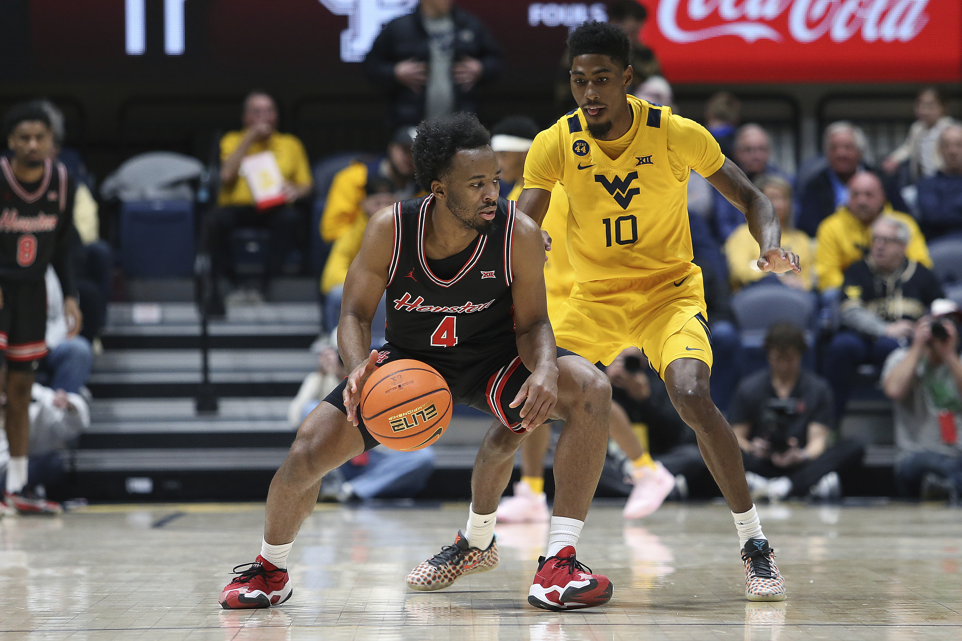 Houston guard L.J. Cryer (4) is defended by West Virginia guard Sencire Harris (10) during the first half of an NCAA college basketball game, Wednesday, Jan. 29, 2025, in Morgantown, W.Va. 