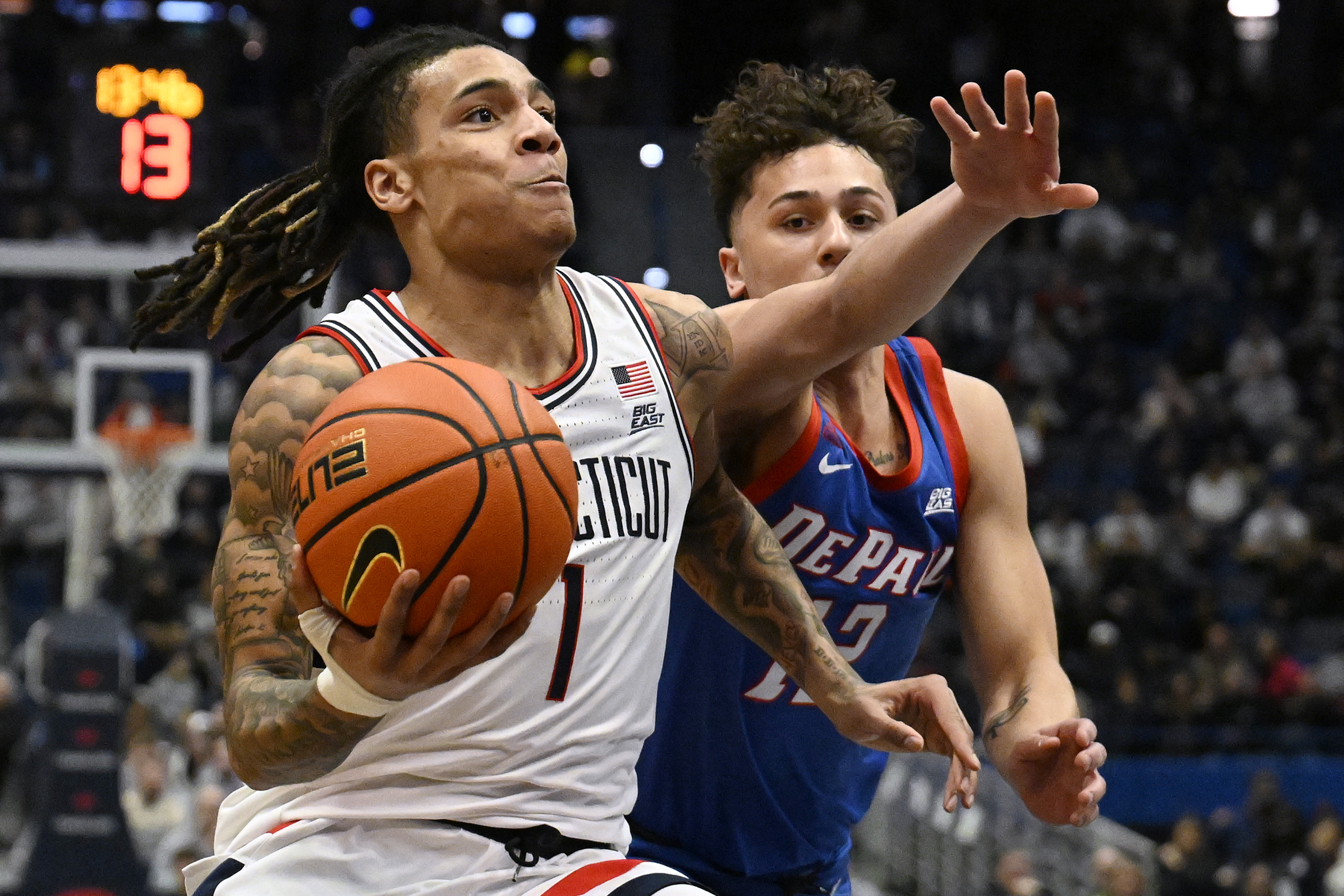UConn guard Solo Ball (1) drives to the basket as DePaul guard Jacob Meyer defends in the first half of an NCAA college basketball game, Wednesday, Jan. 29, 2025, in Hartford, Conn.