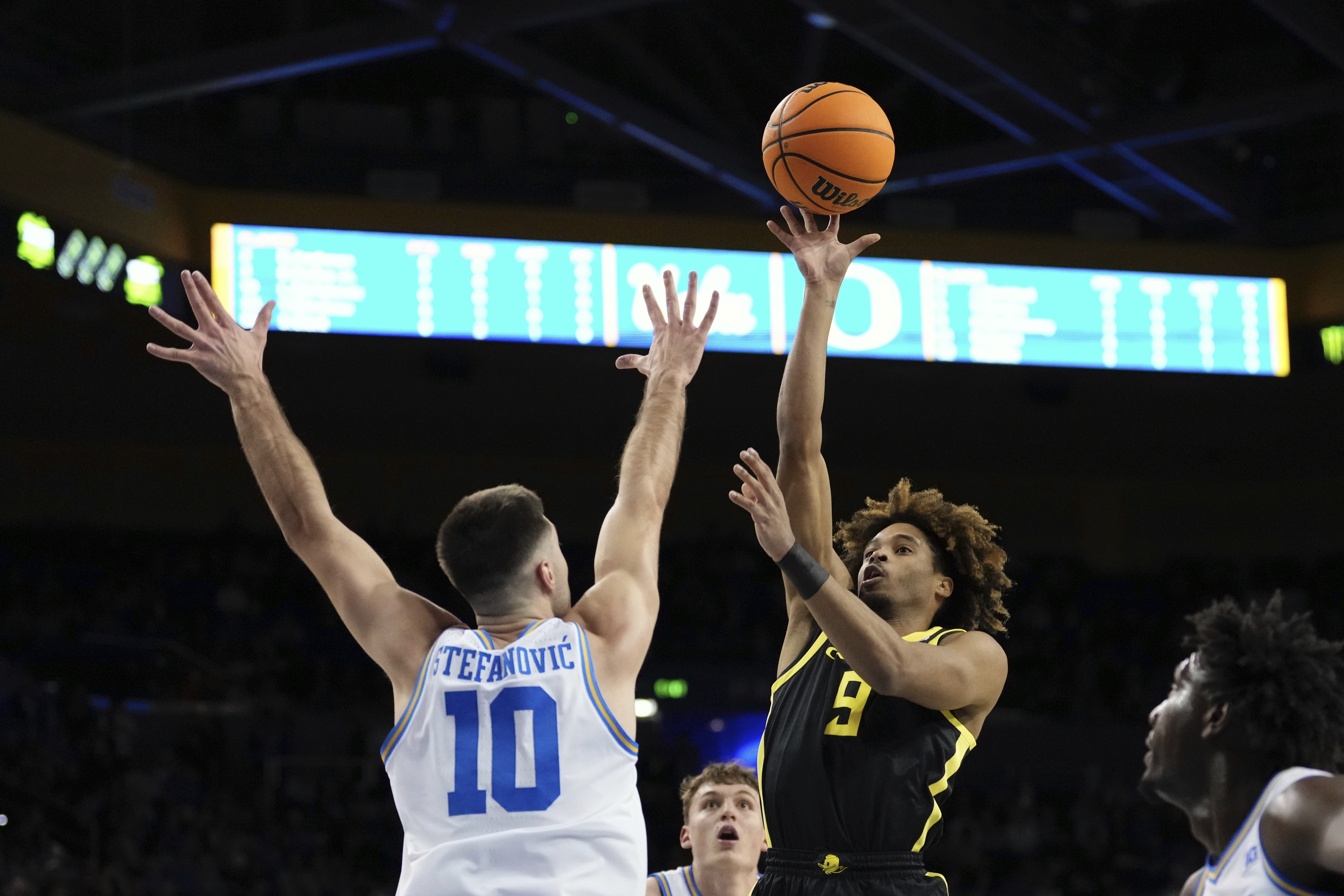 Oregon guard Keeshawn Barthelemy, center, shoots as UCLA guard Lazar Stefanovic defends during the first half of an NCAA college basketball game Thursday, Jan. 30, 2025, in Los Angeles.