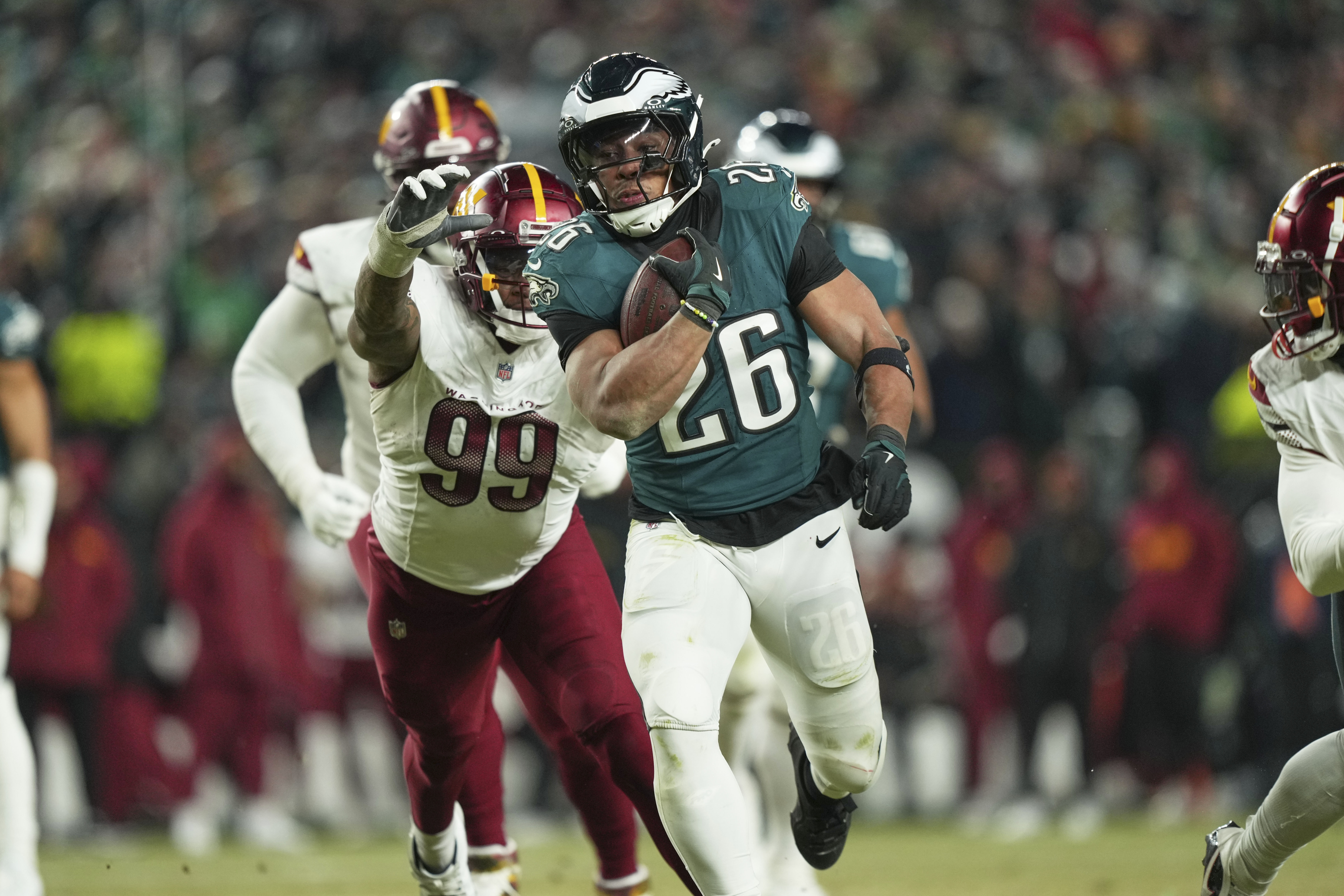 Philadelphia Eagles running back Saquon Barkley (26) runs for a first down as Washington Commanders defensive end Clelin Ferrell (99) defends during the second half of the NFC Championship NFL football game, Sunday, Jan. 26, 2025, in Philadelphia. 