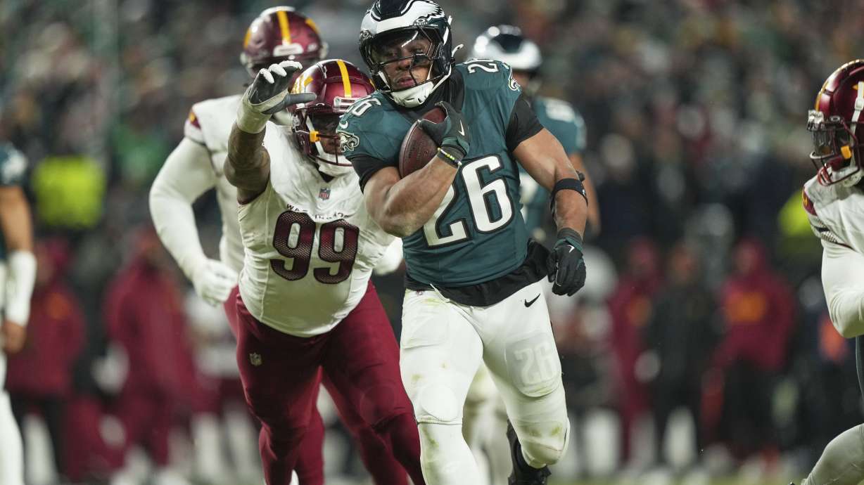 Philadelphia Eagles running back Saquon Barkley (26) runs for a first down as Washington Commanders defensive end Clelin Ferrell (99) defends during the second half of the NFC Championship NFL football game, Sunday, Jan. 26, 2025, in Philadelphia.