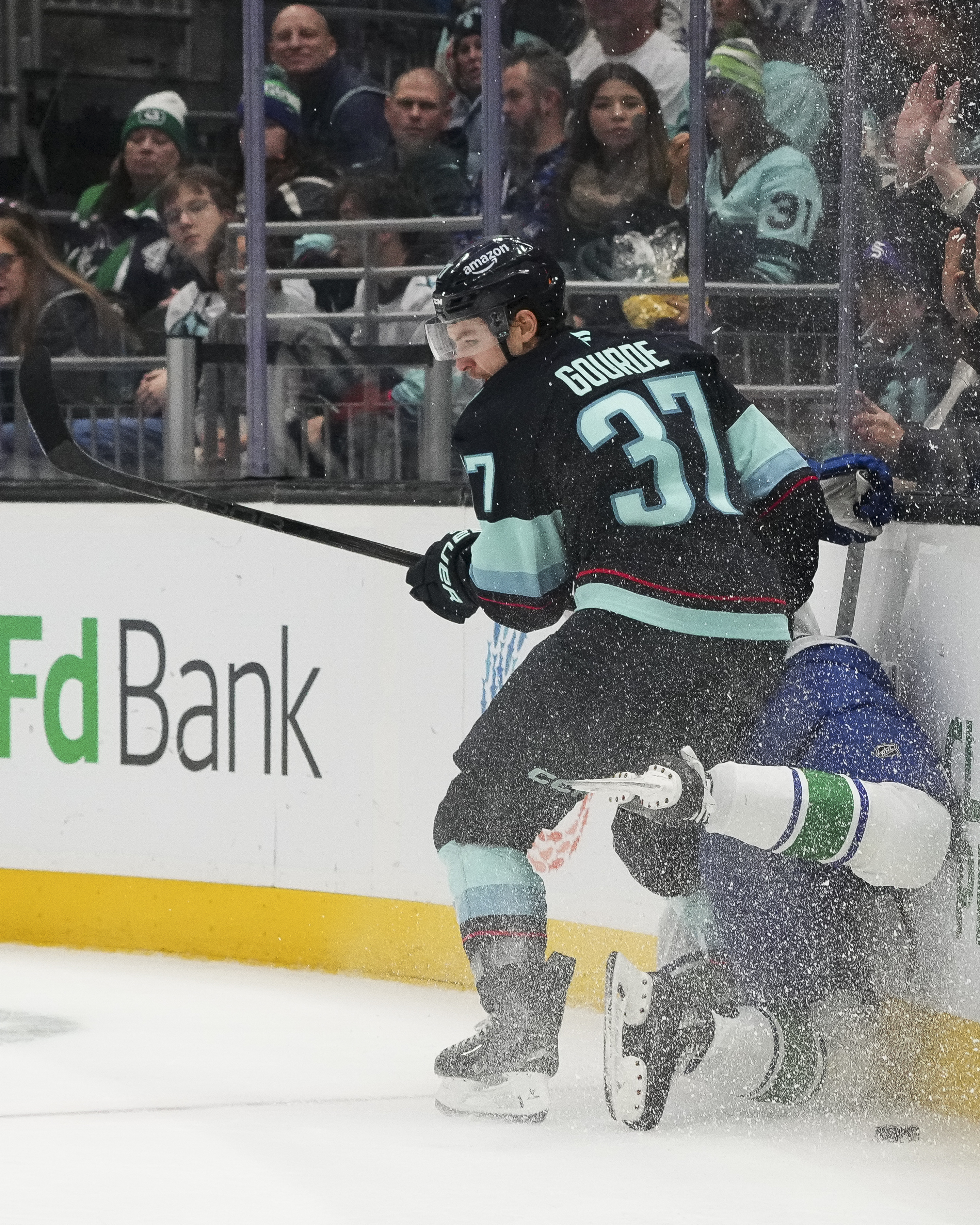 Seattle Kraken center Yanni Gourde checks Vancouver Canucks defenseman Guillaume Brisebois against the boards during the second period of an NHL hockey game Thursday, Jan. 2, 2025, in Seattle. 