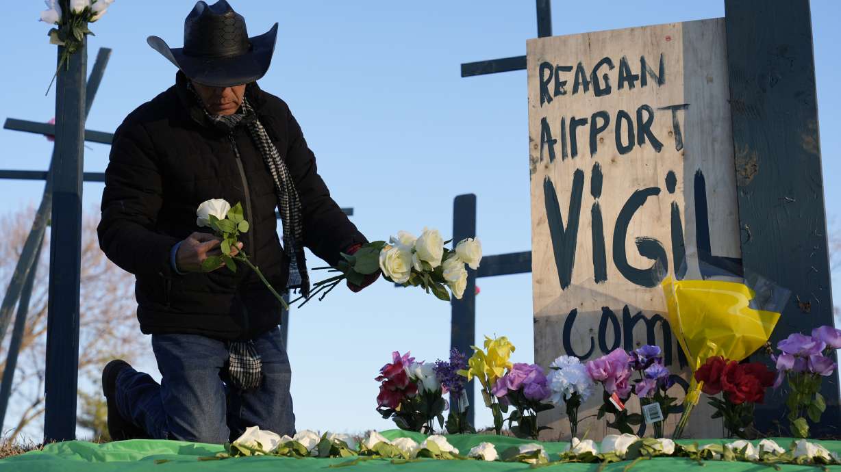 Roberto Marquez, of Dallas, places flowers at a memorial for the 67 victims of a midair collision between an Army helicopter and an American Airlines flight from Kansas near the Ronald Reagan Washington National Airport, Saturday, in Arlington, Va. The name of the third soldier killed in the crash was released Saturday.
