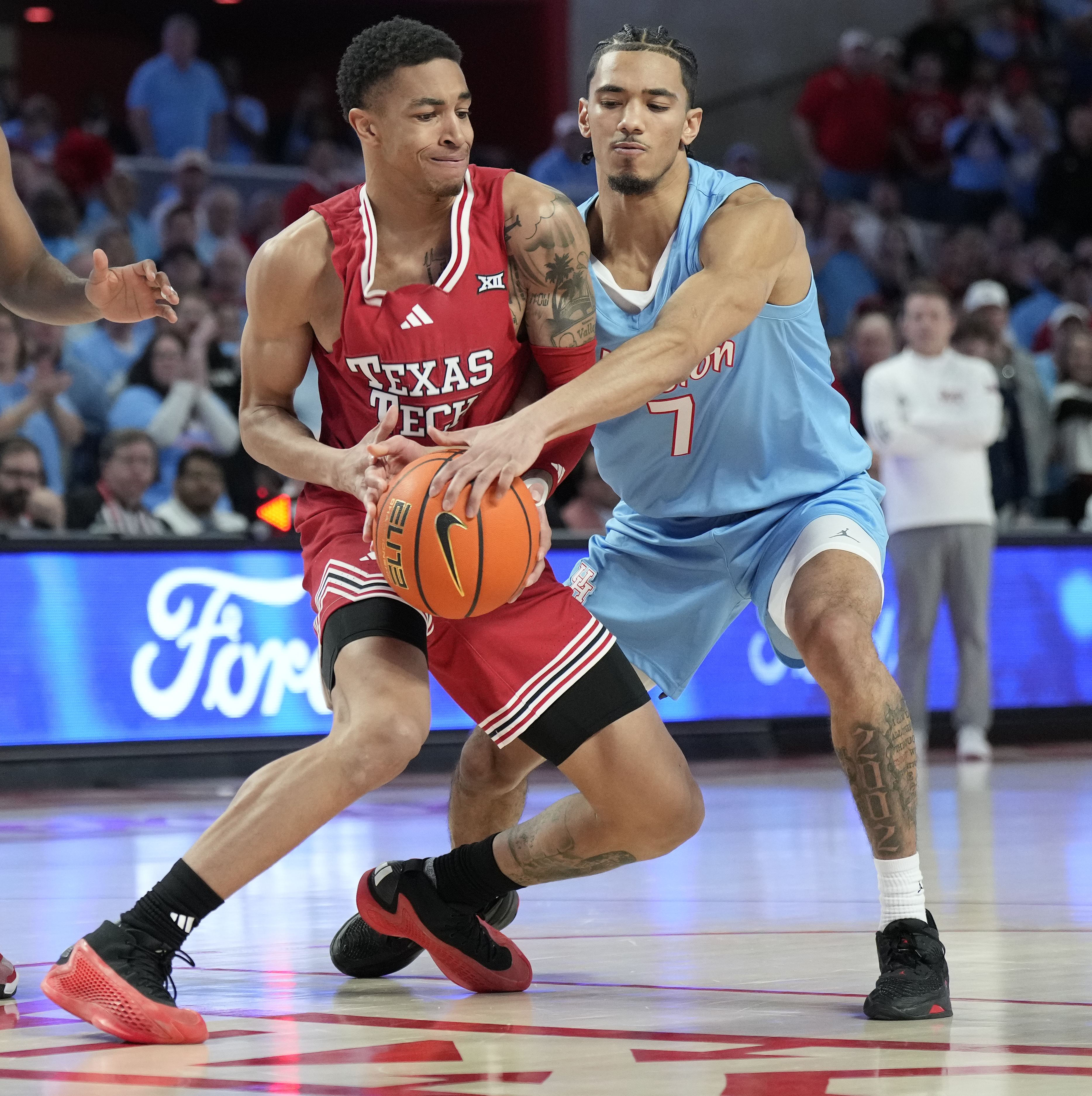 Texas Tech guard Chance McMillian, left, battles against Houston guard Milos Uzan (7) for control of the ball during the first half of an NCAA college basketball game in Houston, Saturday, Feb. 1, 2025. 
