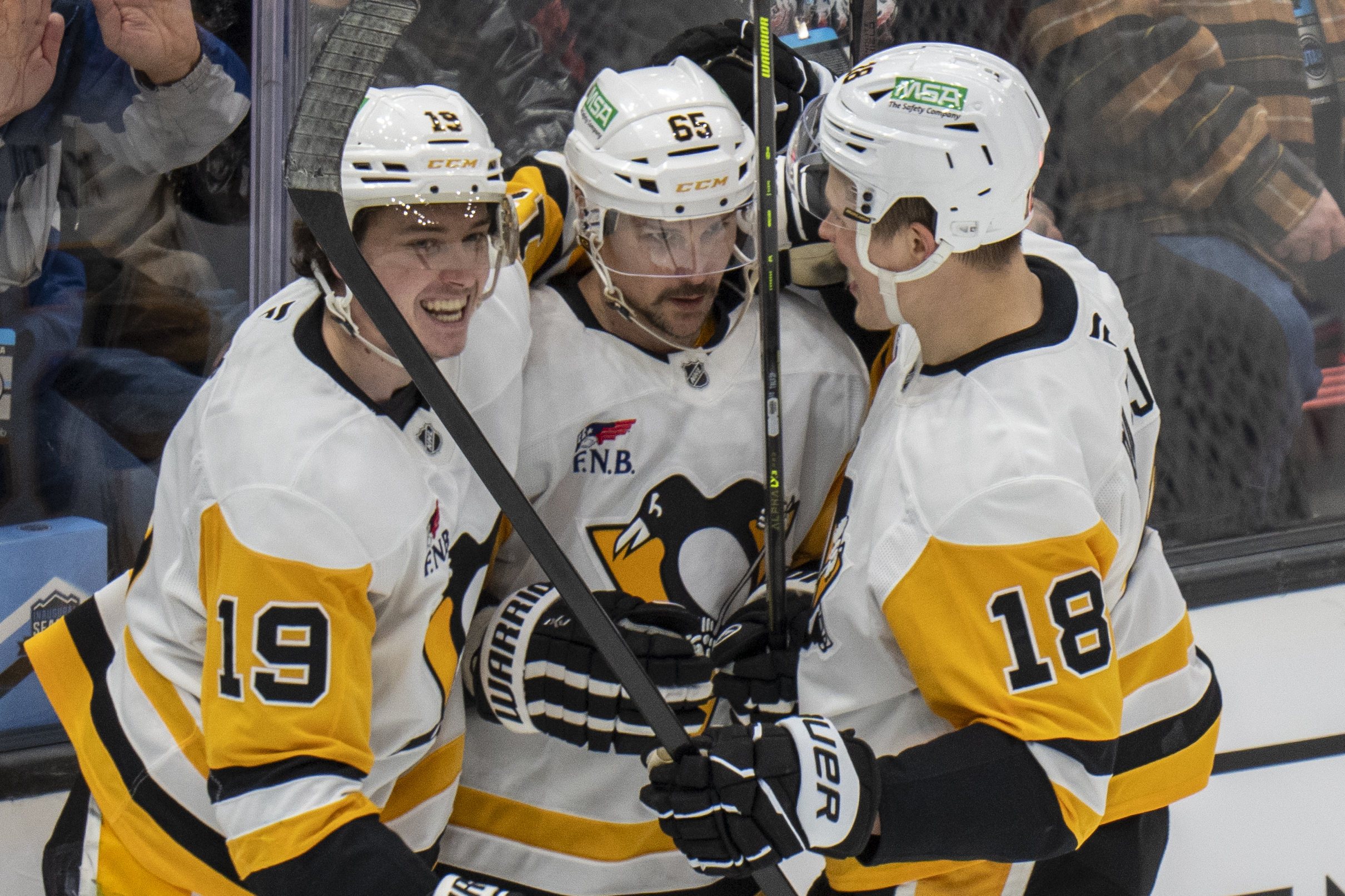 Pittsburgh Penguins center Cody Glass (19) and Pittsburgh Penguins right wing Jesse Puljujarvi (18) hug Pittsburgh Penguins defenseman Erik Karlsson, middle, after he scored the tying goal, during the third period of an NHL hockey game against the Utah Hockey Club Wednesday, Jan. 29, 2025, in Salt Lake City. 