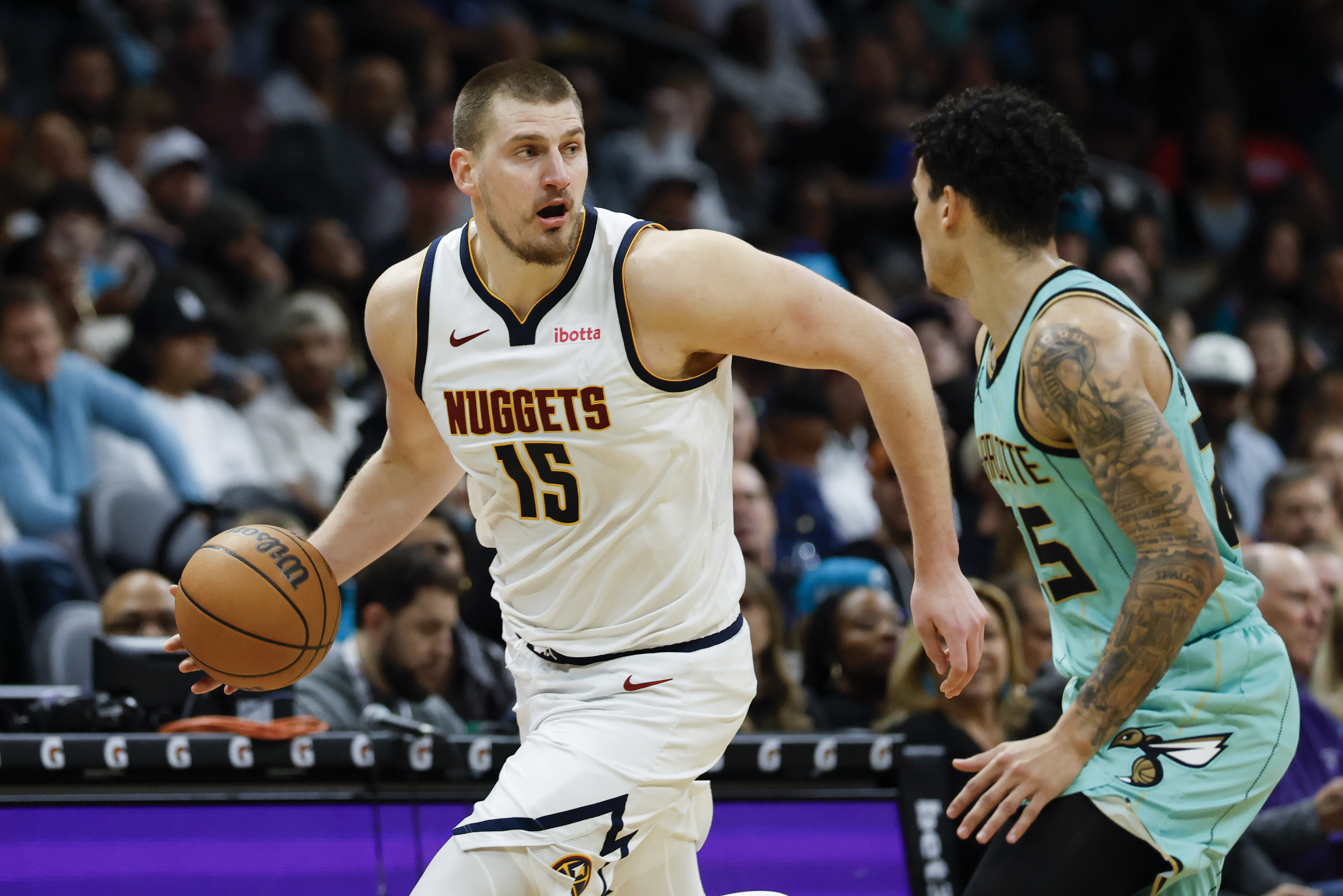 Denver Nuggets center Nikola Jokic (15) brings the ball up court against Charlotte Hornets guard KJ Simpson during the second half of an NBA basketball game in Charlotte, N.C., Saturday, Feb. 1, 2025. 
