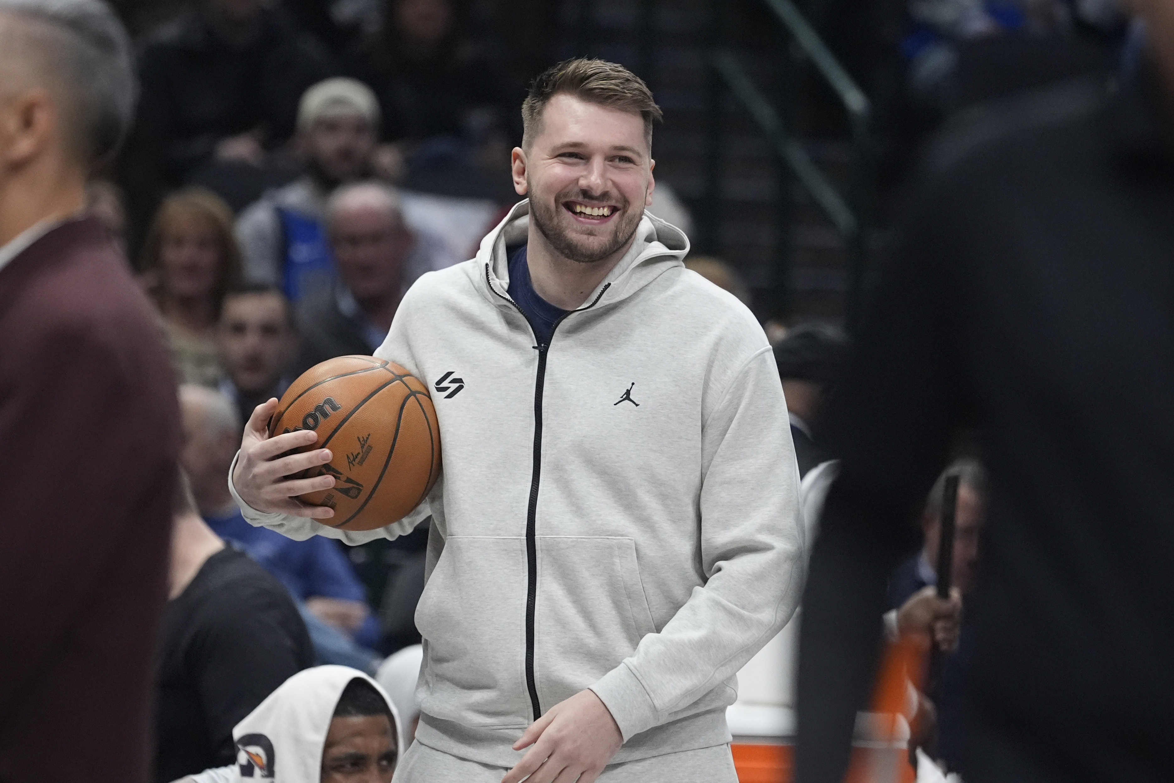 Injured Dallas Mavericks guard Luka Doncic smiles as he holds the game ball in a time out during the first half of an NBA basketball game against the Minnesota Timberwolves Wednesday, Jan. 22, 2025, in Dallas.