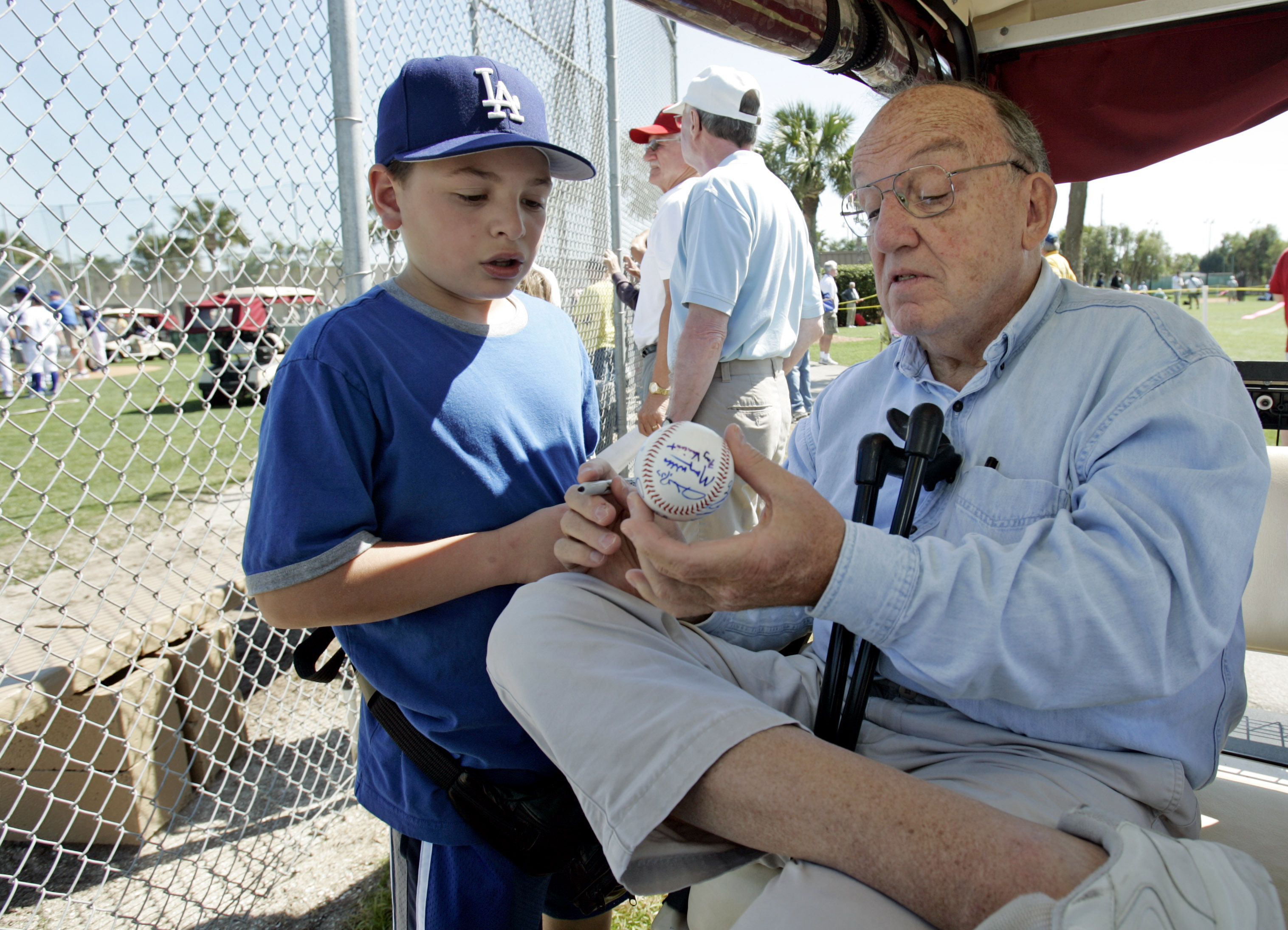 FILE - Former Major League Baseball Commissioner Fay Vincent signs an autograph for Louis Carrons, 12, of Rancho Cucamonga, Calif., during Los Angeles Dodgers baseball spring training in Vero Beach, Fla., March 1, 2006.