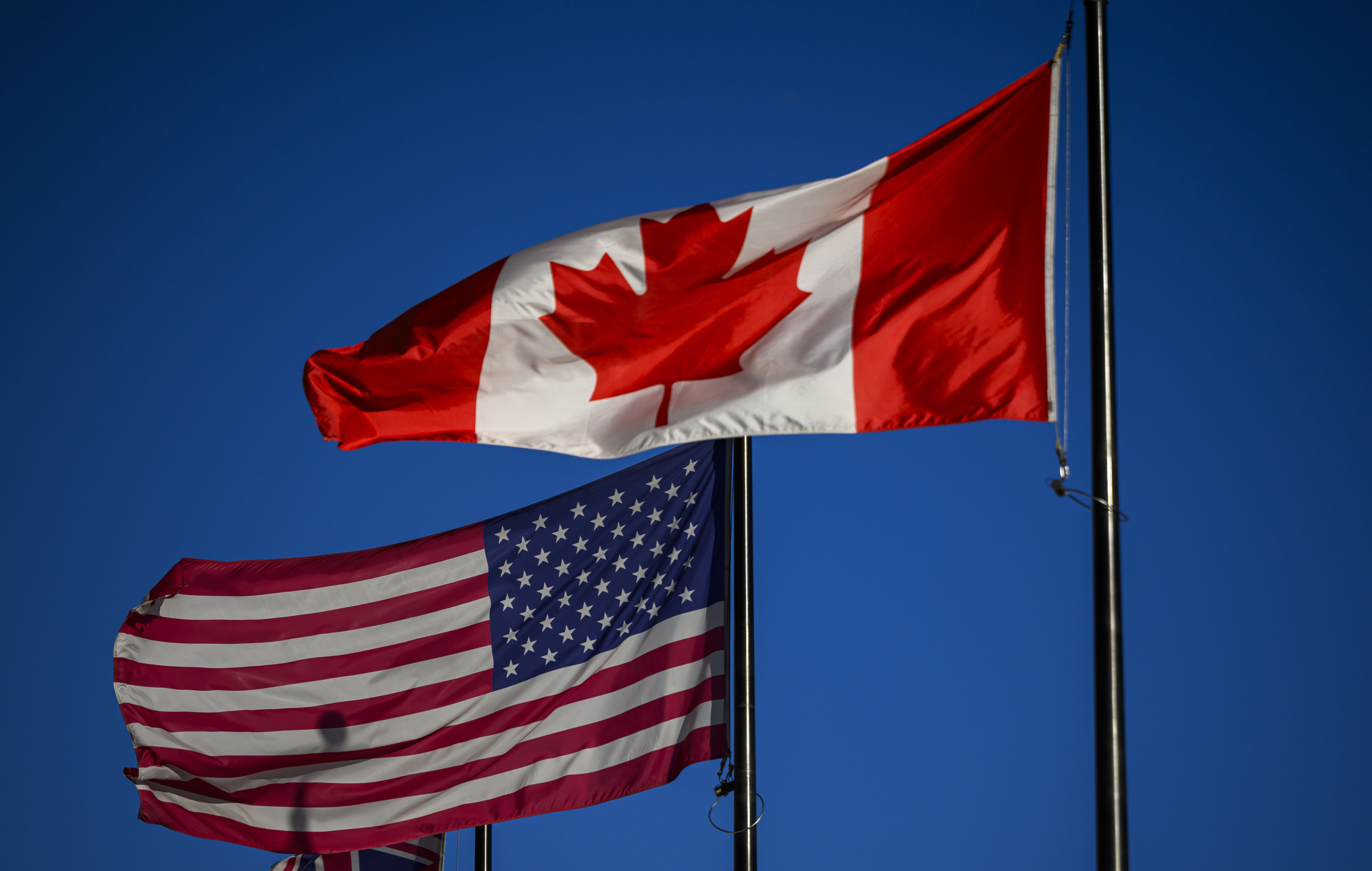 The flags of Canada and the United States fly outside a hotel in downtown Ottawa, on Saturday, Feb. 1, 2025. 