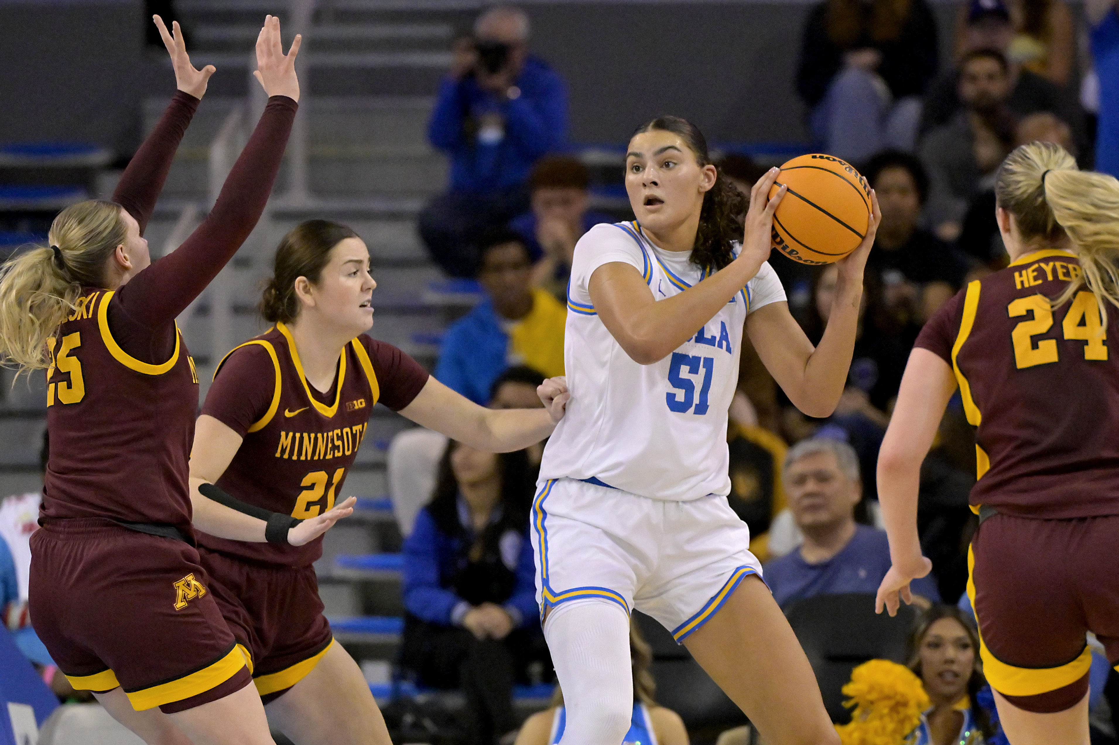 UCLA center Lauren Betts (51) is defended by Minnesota guard Grace Grocholski, left, forward Annika Stewart, second from left, and forward Mallory Heyer (24) during the first half of an NCAA college basketball game Sunday, Feb. 2, 2025, in Los Angeles.