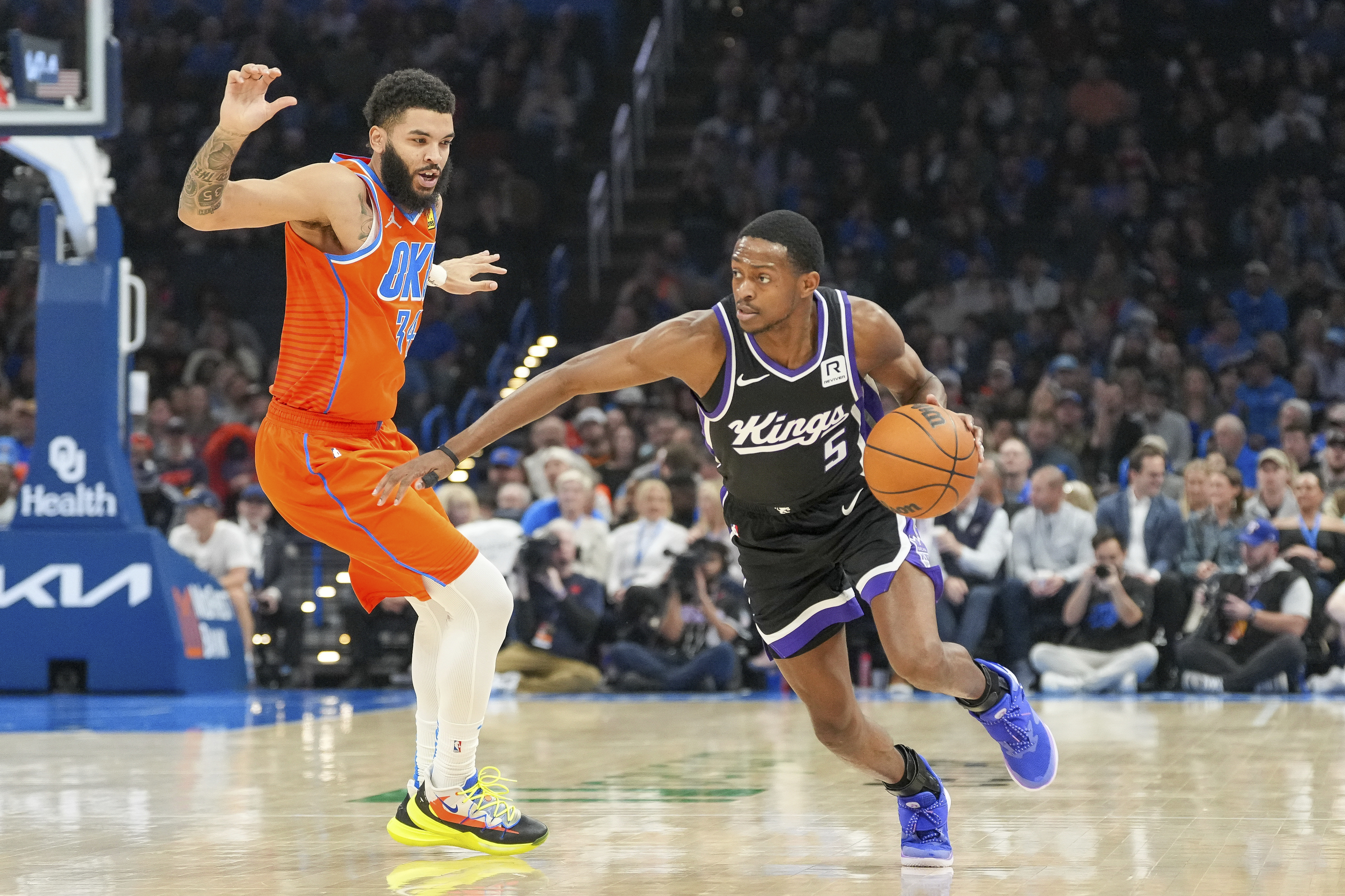 Sacramento Kings guard De'Aaron Fox, right, drives past Oklahoma City Thunder forward Kenrich Williams, left, during the first half of an NBA basketball game, Saturday, Feb. 1, 2025, in Oklahoma City. 