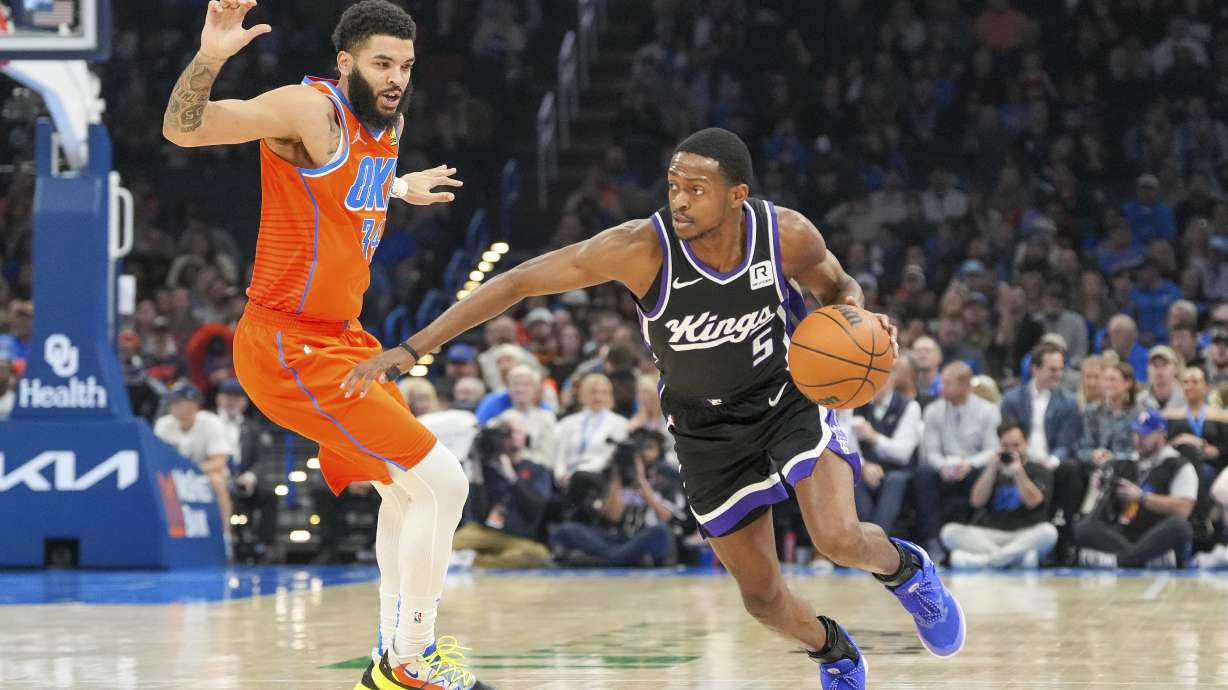 Sacramento Kings guard De'Aaron Fox, right, drives past Oklahoma City Thunder forward Kenrich Williams, left, during the first half of an NBA basketball game, Saturday, Feb. 1, 2025, in Oklahoma City.