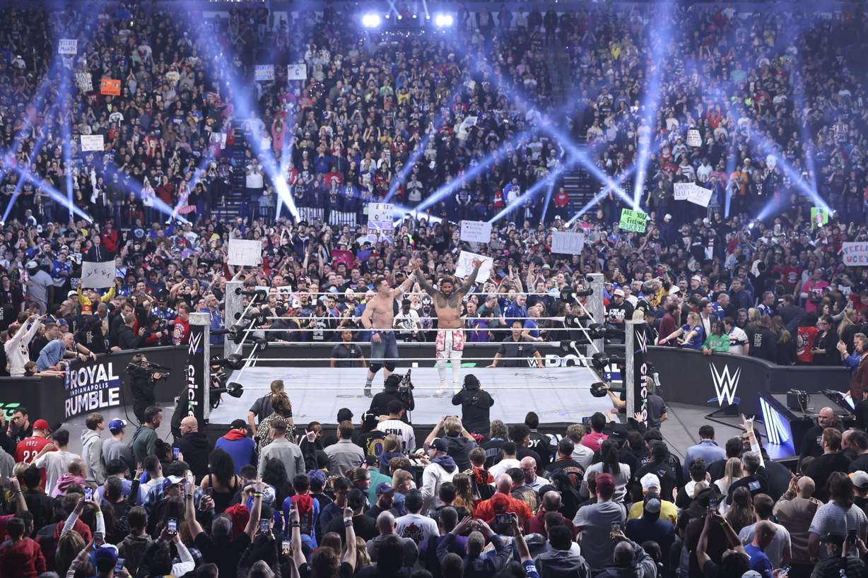 This image provided by the WWE shows John Cena holding up the arm of Jey Uso during a Royal Rumble event in Indianapolis.