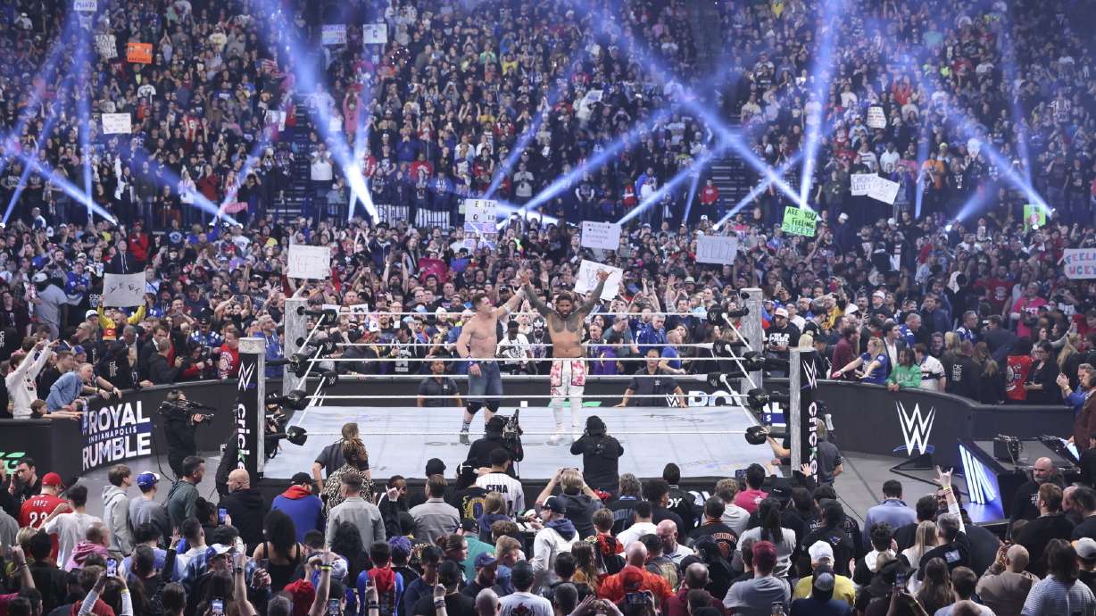 This image provided by the WWE shows John Cena holding up the arm of Jey Uso during a Royal Rumble event in Indianapolis.