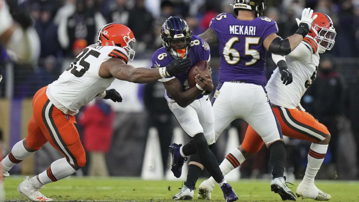 Baltimore Ravens quarterback Lamar Jackson (8) runs with the ball as Cleveland Browns defensive end Myles Garrett, left, defends during the first half of an NFL football game Saturday, Jan. 4, 2025, in Baltimore.