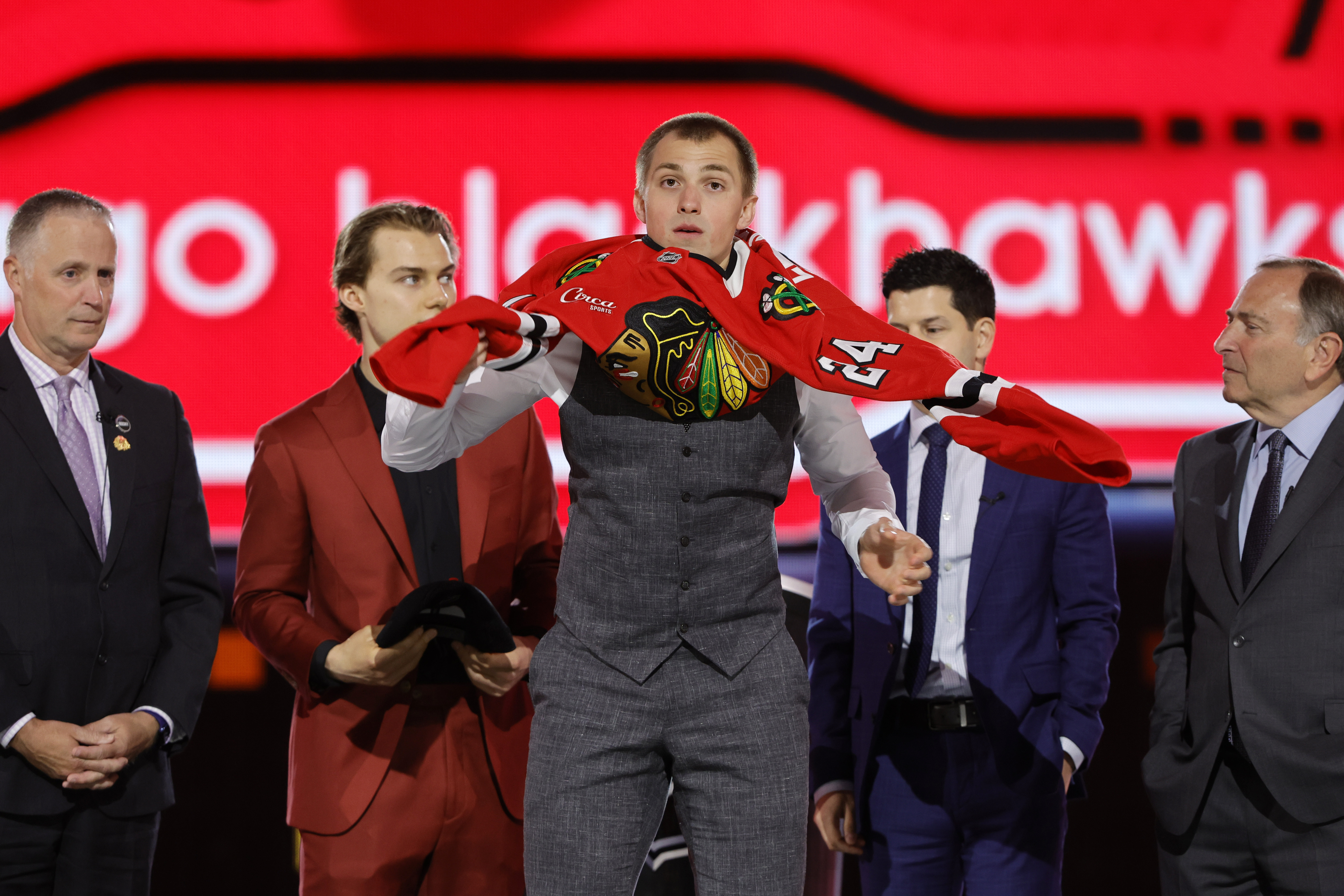 FILE - Artyom Levshunov, center, puts on a jersey after being selected by the Chicago Blackhawks during the first round of the NHL hockey draft, June 28, 2024, in Las Vegas. 