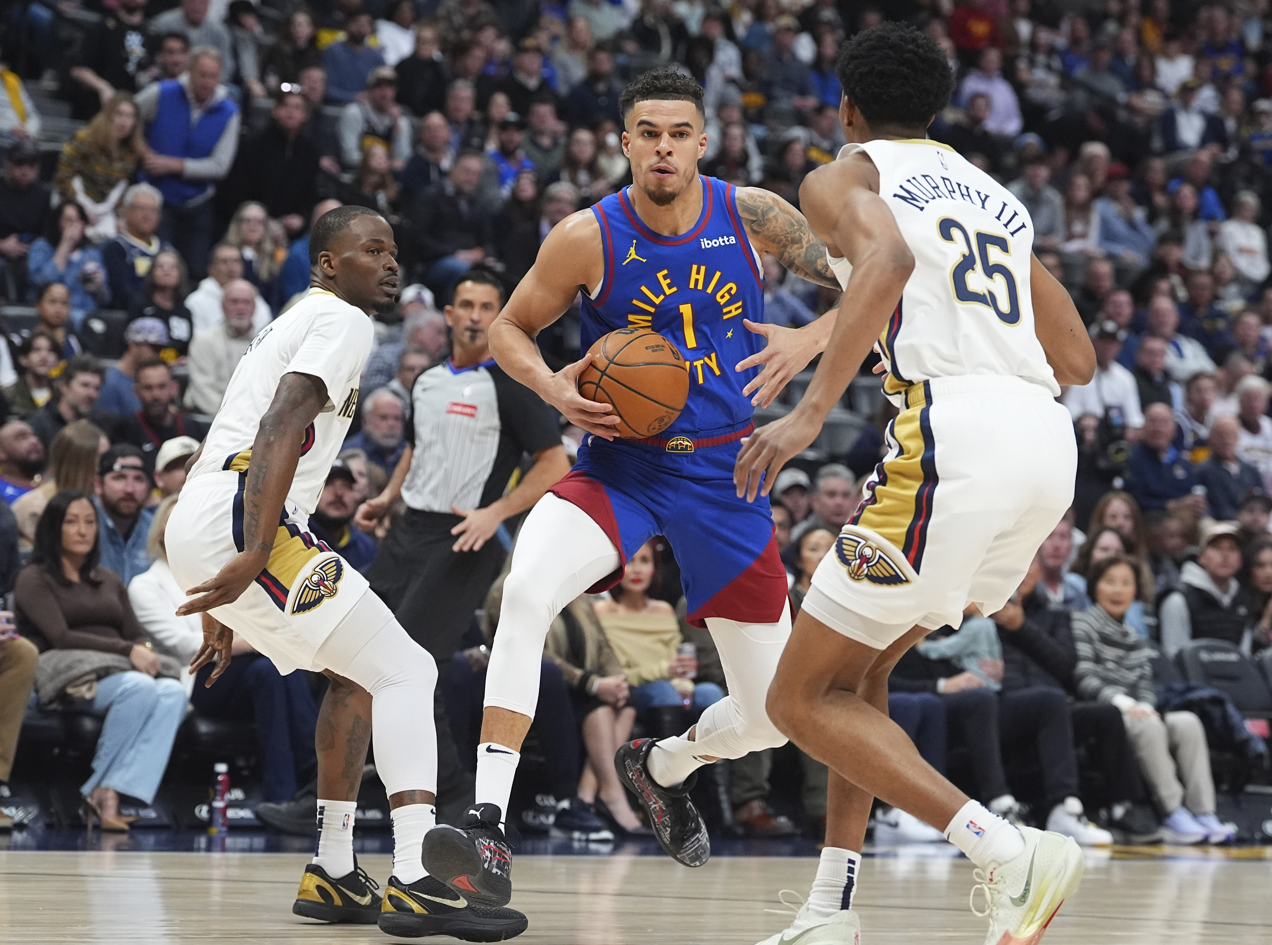 Denver Nuggets forward Michael Porter Jr., center, drives to the basket as New Orleans Pelicans guards Javonte Green, left, and Trey Murphy III, right, defend in the first half of an NBA basketball game Monday, Feb. 3, 2025, in Denver. 